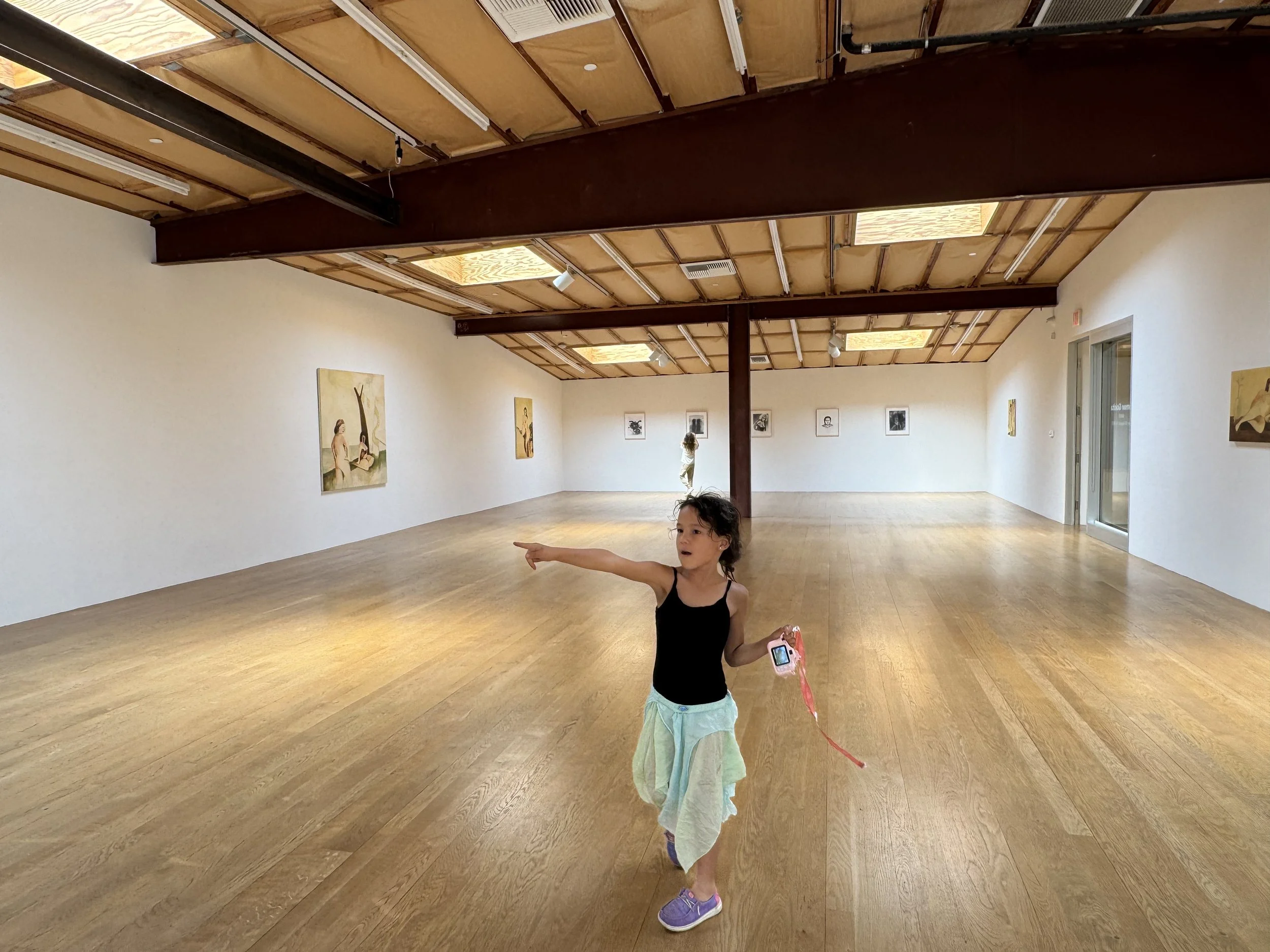 young girl pointing excitingly at a painting in a gallery