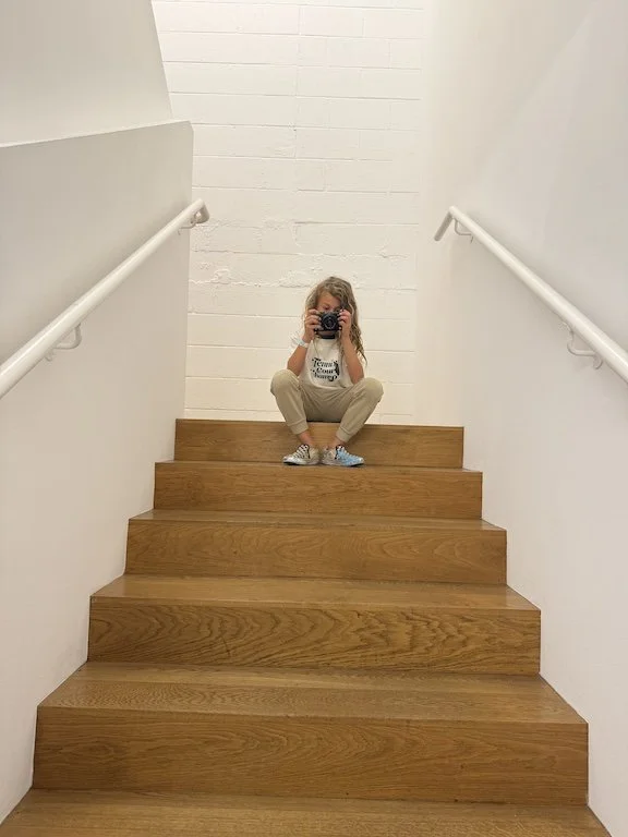 boy sitting at the top of the stairs with a camera in his hand
