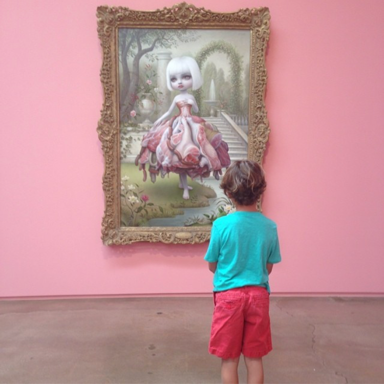young boy in front of a Mark Ryden painting