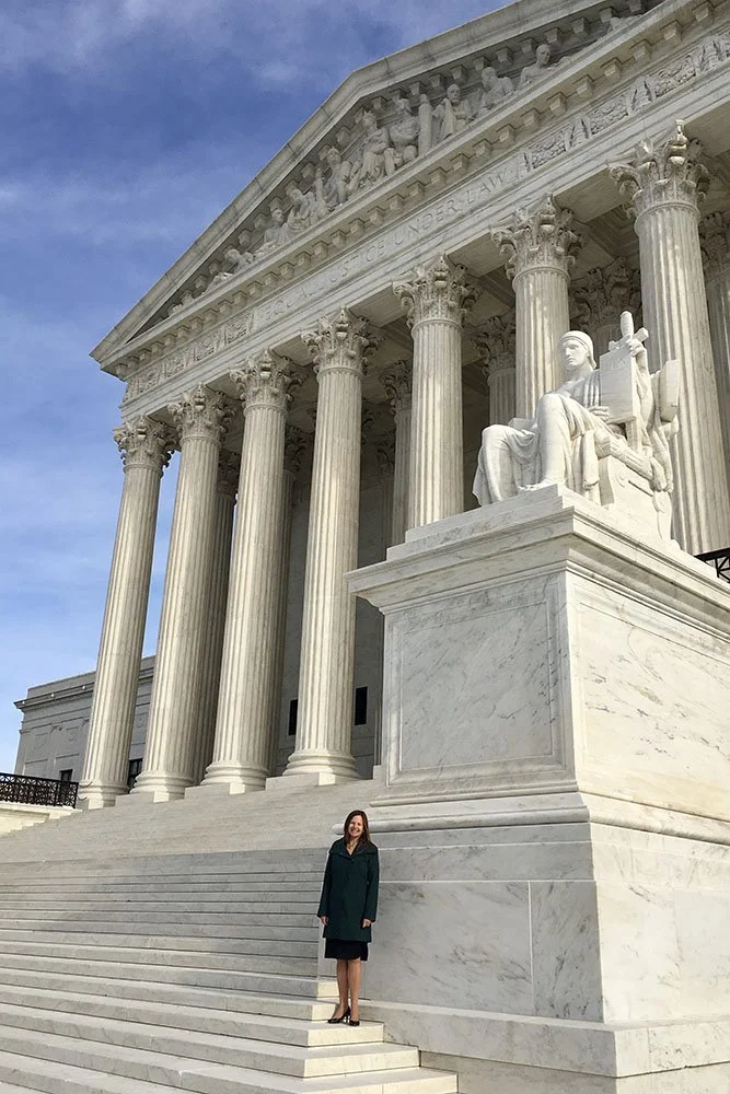 A woman standing on the steps of the U.S. Capitol building in Washington D.C. during the day.