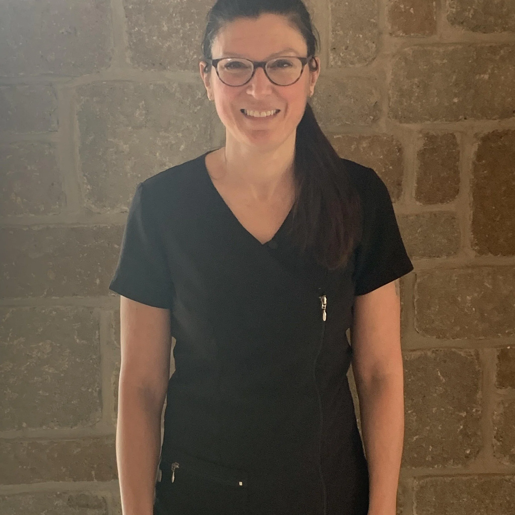 Élizabeth Vibert, massothérapeute, se tenant devant un mur de pierre