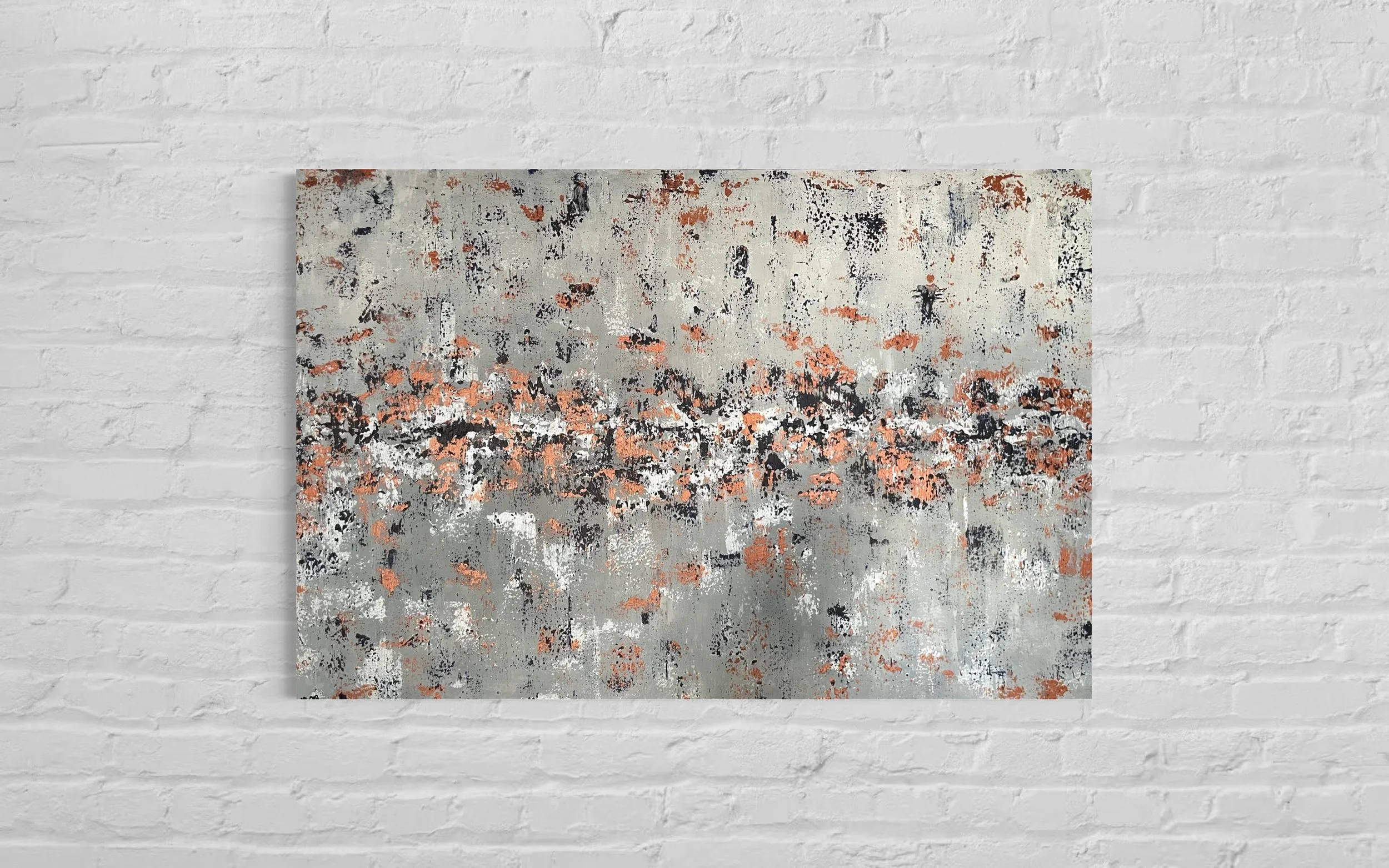 Abstract painting with gray, black, white, and orange splatters on a white brick wall background.