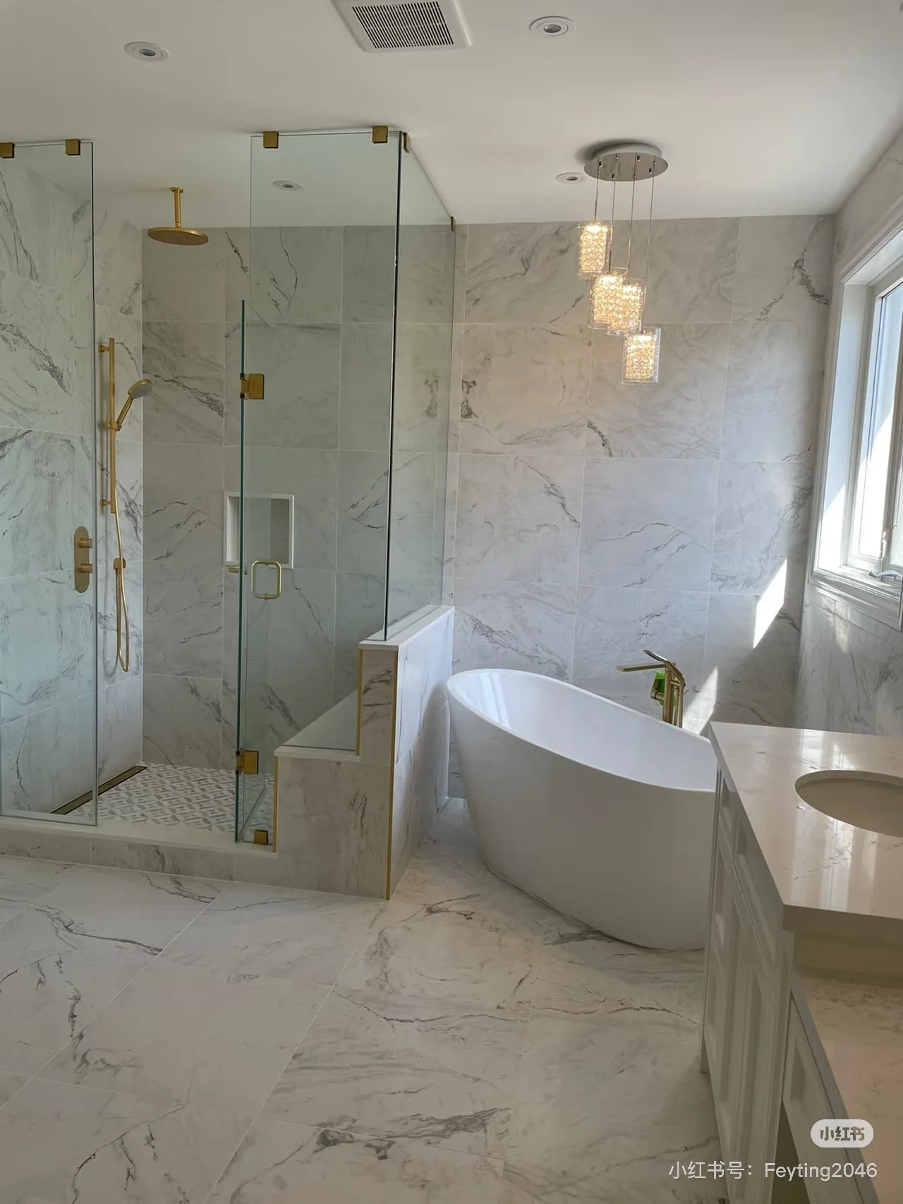 Modern bathroom featuring a glass-enclosed shower with gold fixtures, a white freestanding bathtub, and a marble vanity with a sink, illuminated by a window and decorative pendant lights.