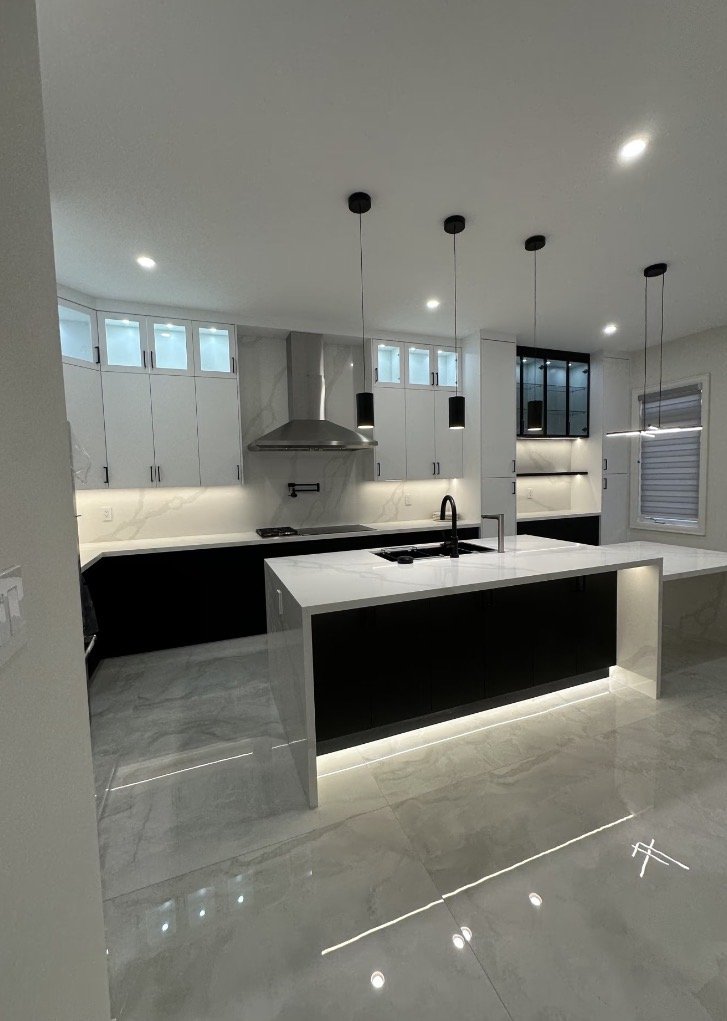 Modern kitchen with white and black cabinetry, marble countertops, stainless steel range hood, and pendant lighting.