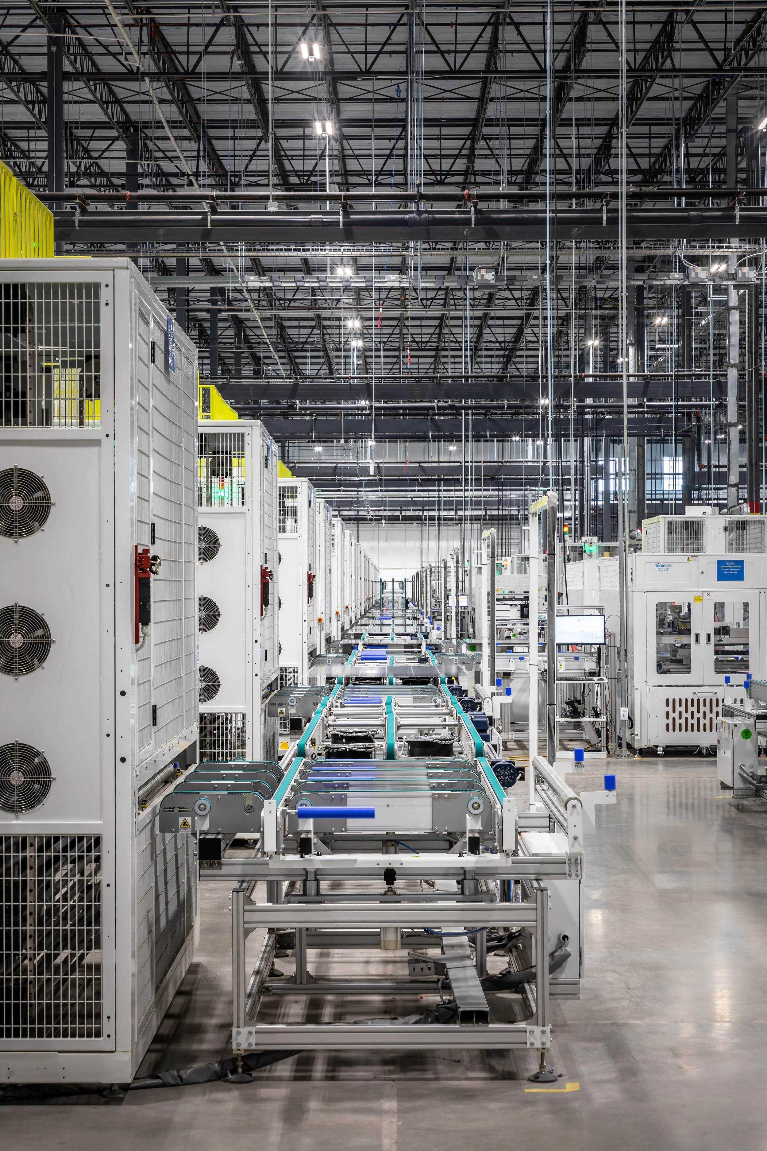 A modern, brightly lit industrial facility in Dallas, with rows of white equipment from a leading solar panel manufacturer extending symmetrically along a central walkway.