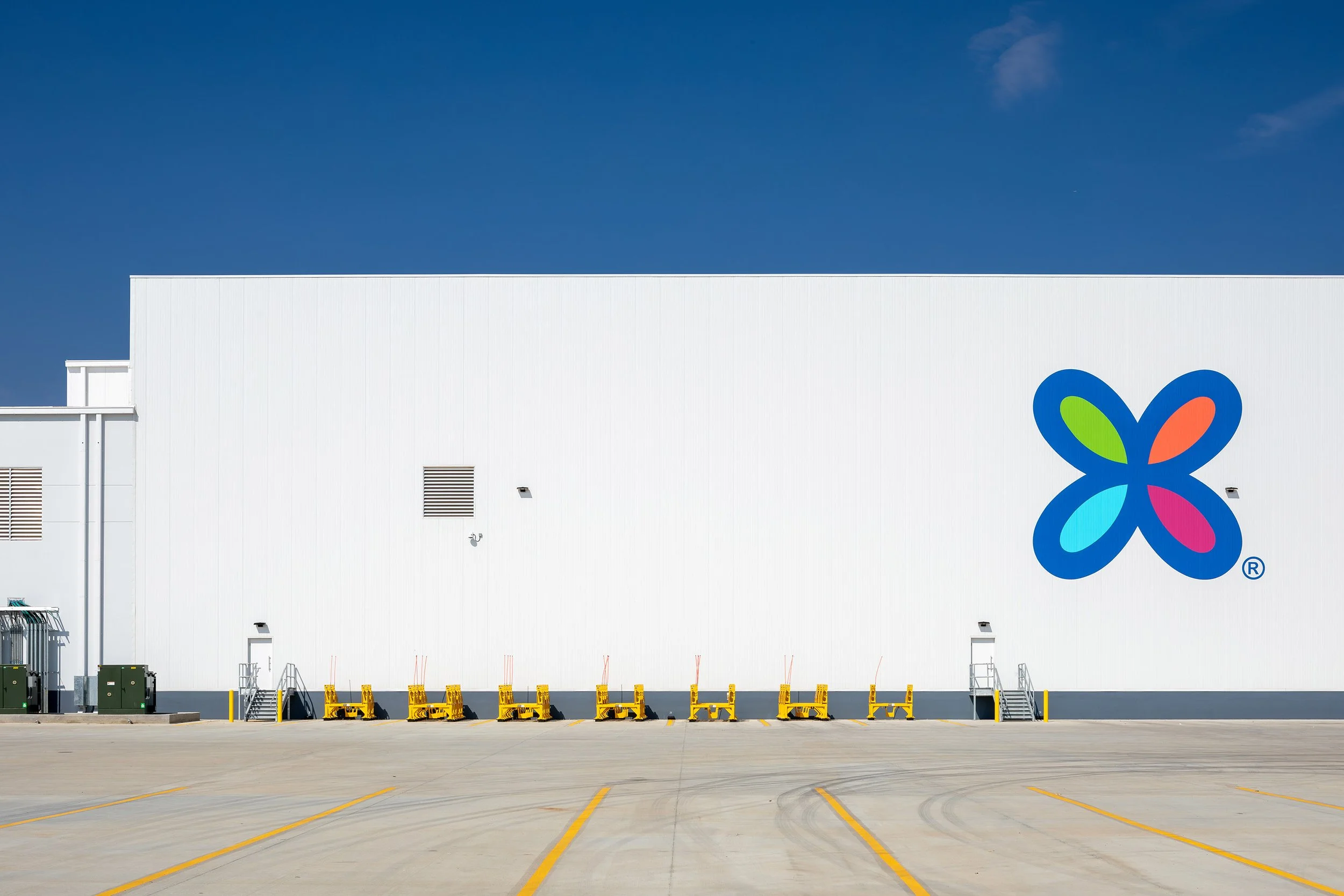 A large white Georgia Pacific building with the Dixie ogo, yellow equipment outside, and a clear blue sky above—a facility for paper products manufacturing.