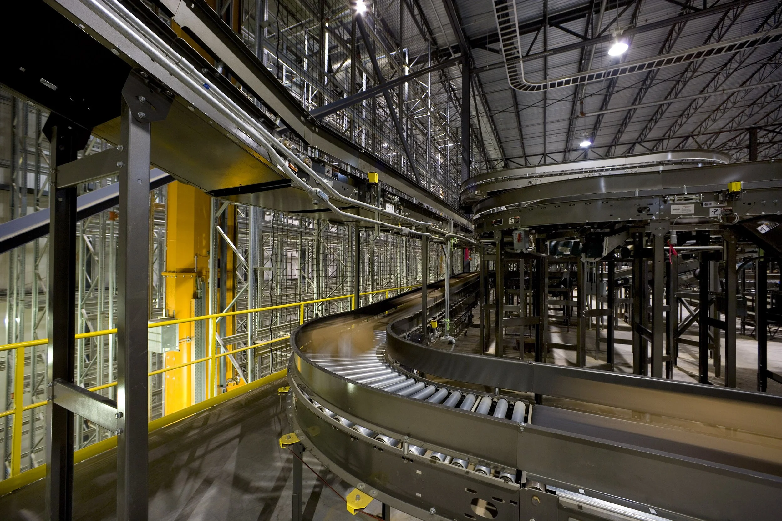 Curved metal conveyor belts inside a large, modern Texas warehouse with metal beams and overhead lights streamline food processing operations.