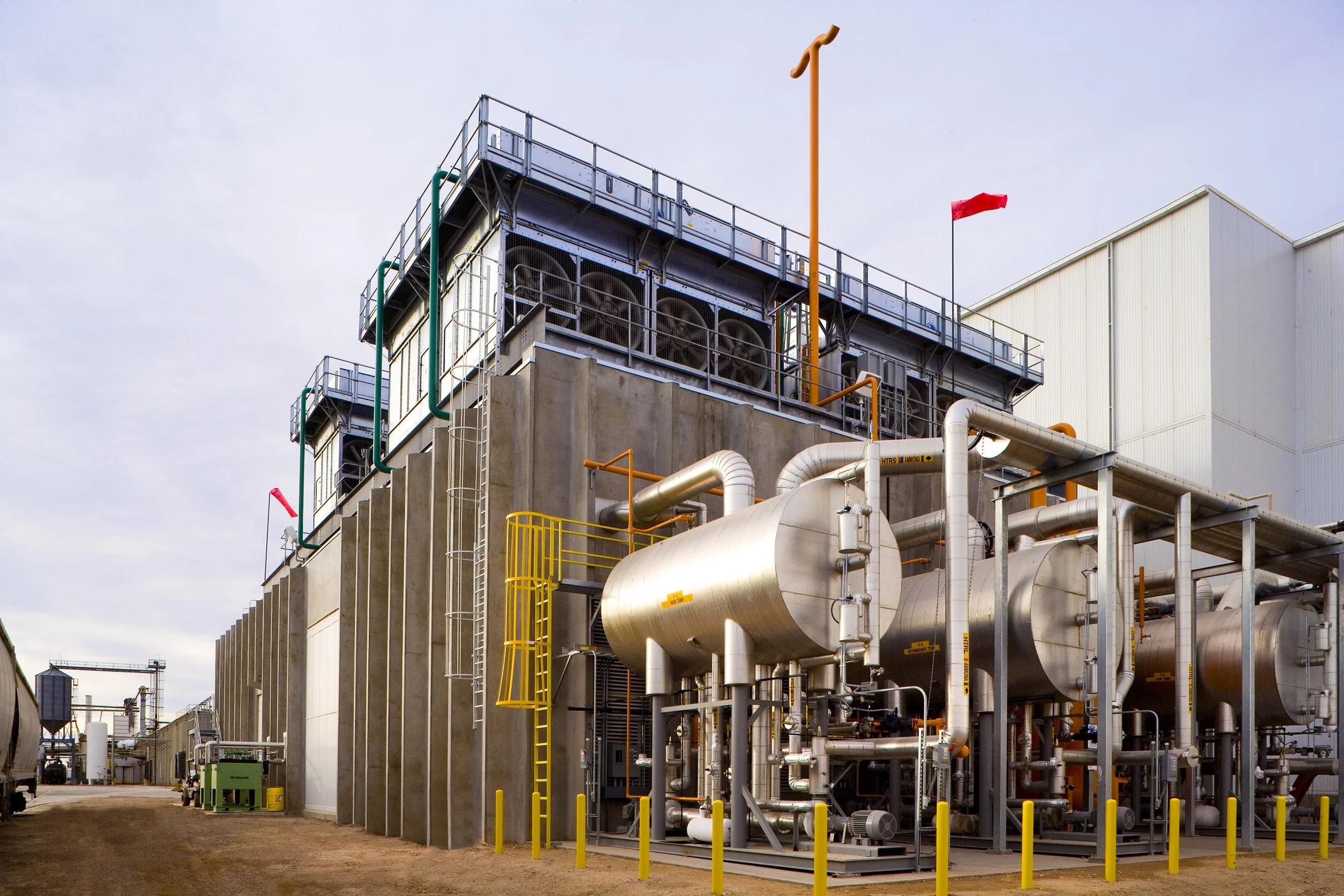Large industrial facility in Texas with storage tanks, pipes, safety railings, and red wind direction flags—ideal for industrial photography.