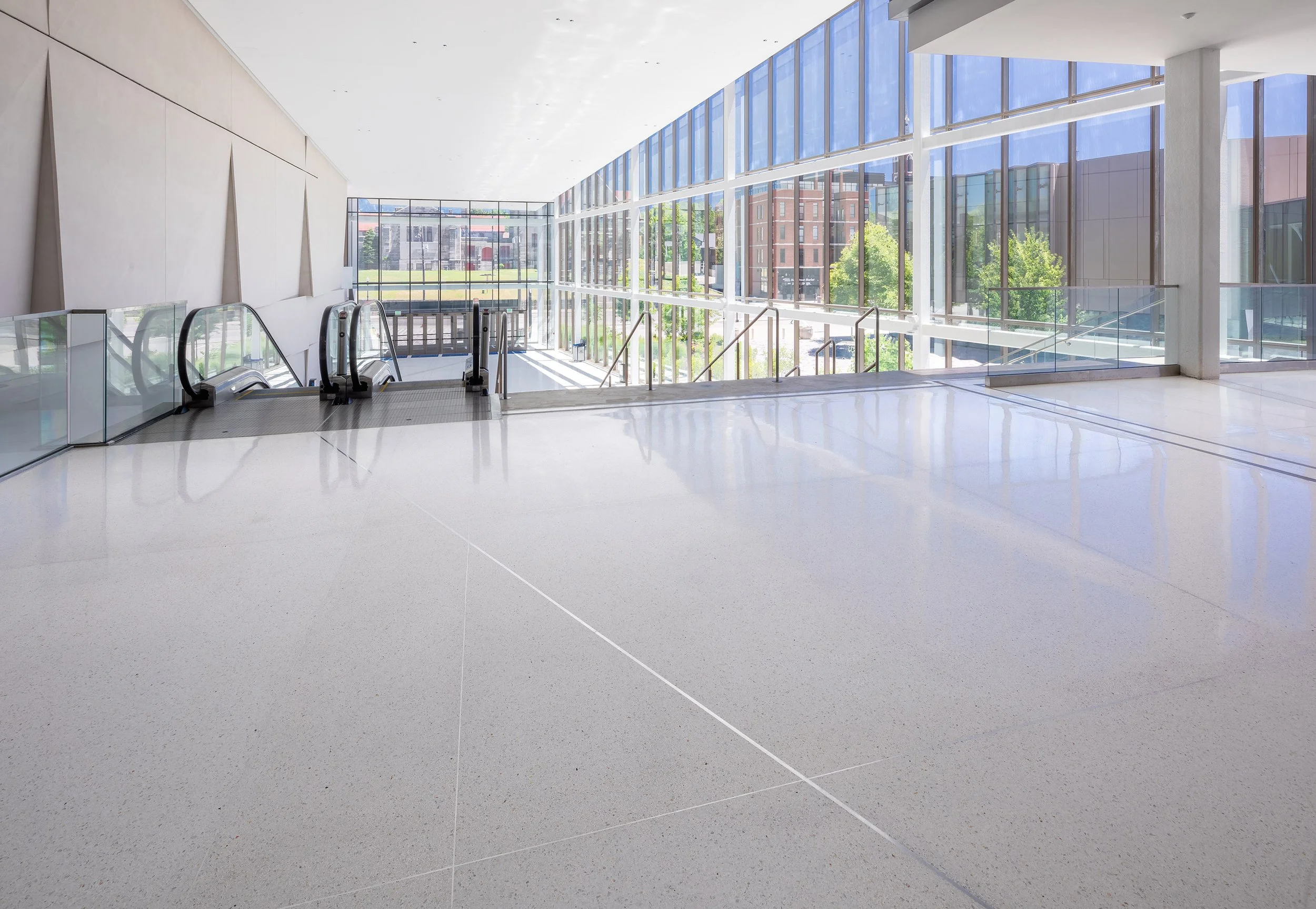 Spacious atrium in Central Bank Center with large windows, two escalators, and glossy light-colored flooring with access to Rupp Arena.