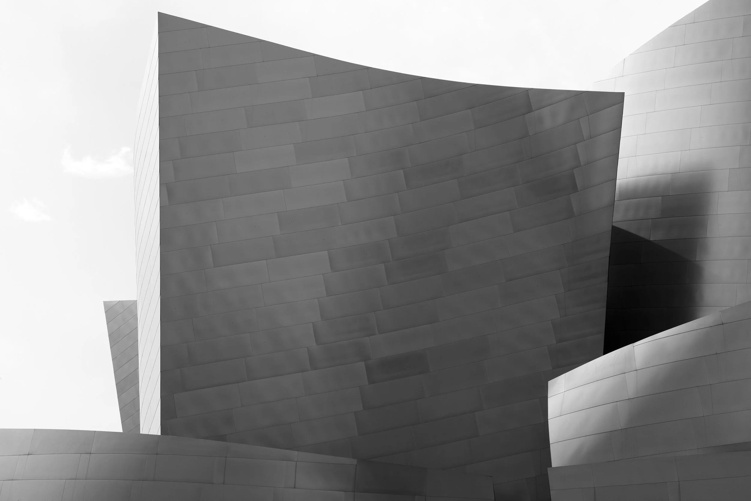 Curved, metallic building facade with smooth, overlapping panels in black and white.
