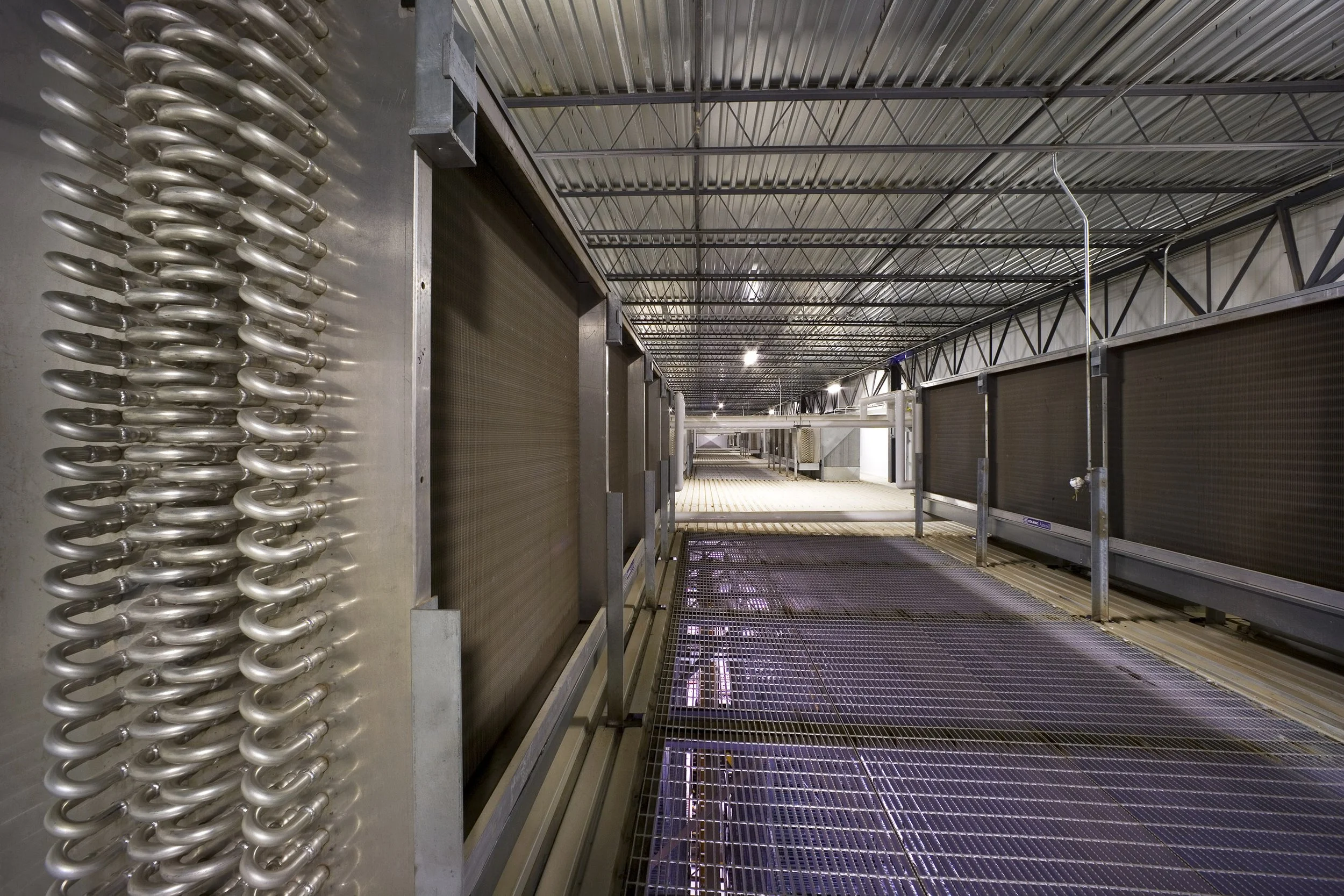 Industrial interior in Texas with refrigeration coils, grates, and large ventilation units—a food process facility under a corrugated metal ceiling.