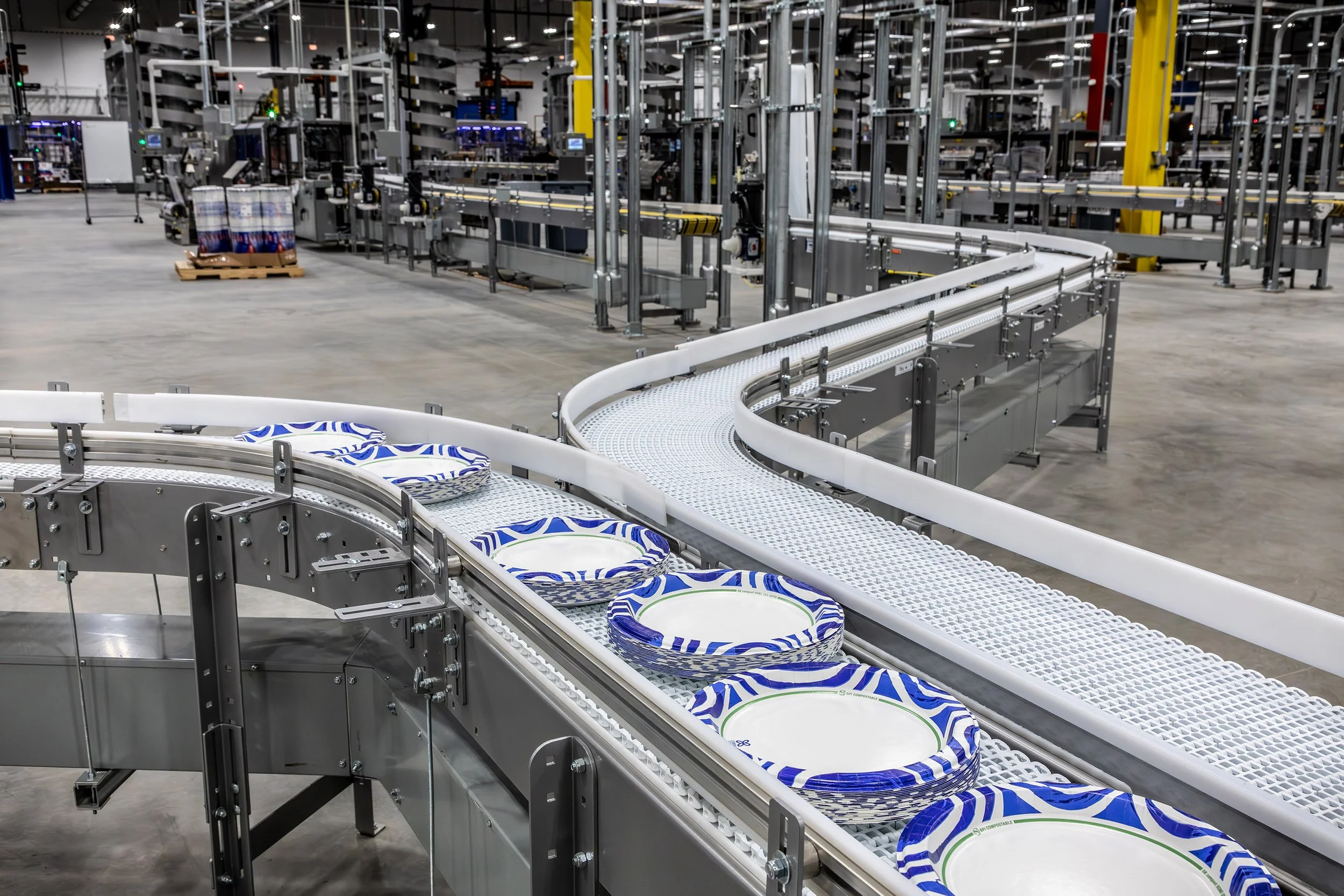 A conveyor belt transports stacks of patterned paper plates, showcasing products manufacturing at Georgia Pacific.