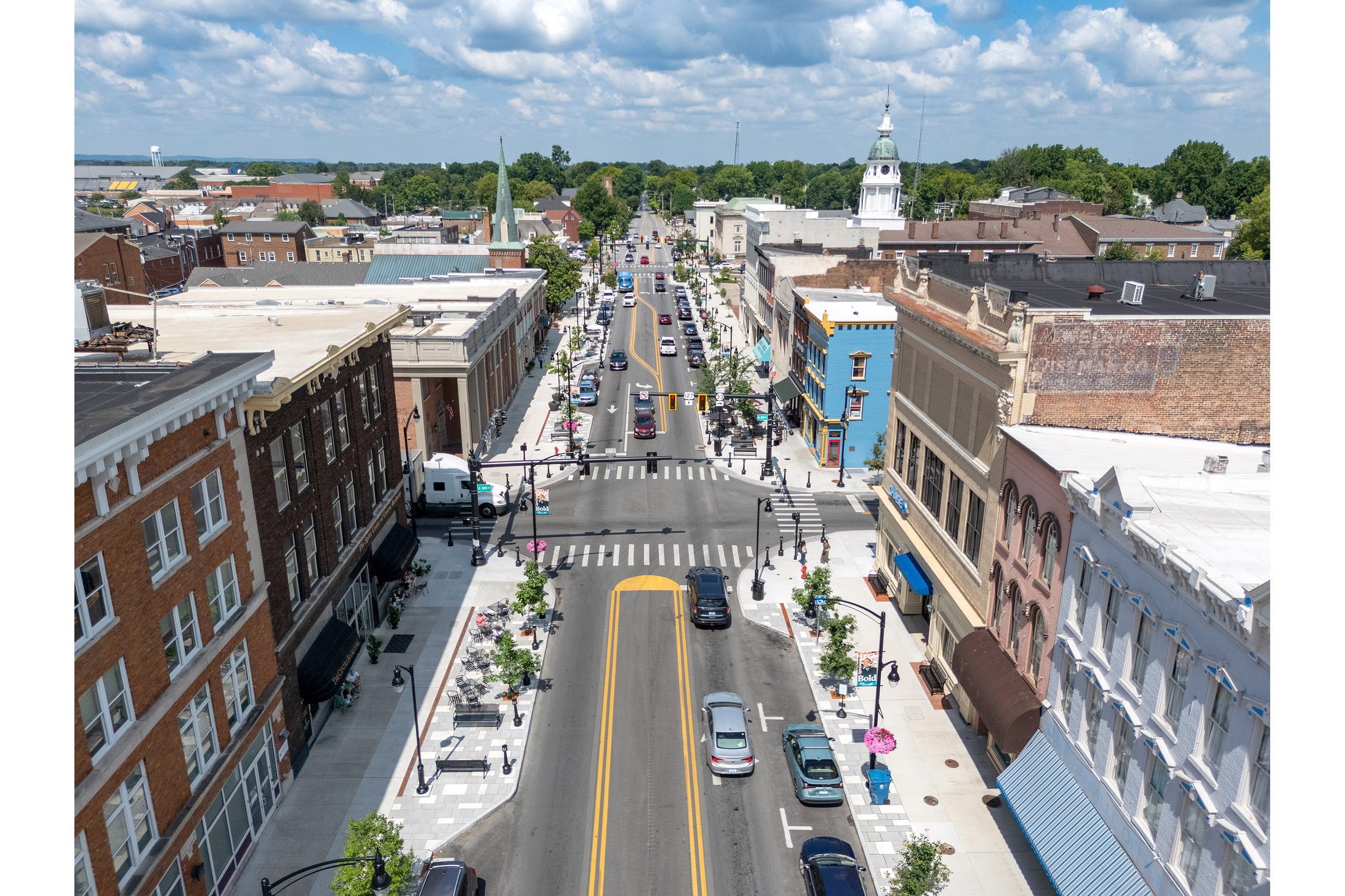 Aerial view of a main street lined with historic buildings, showcasing the architectural charm and vibrant life of a small town.