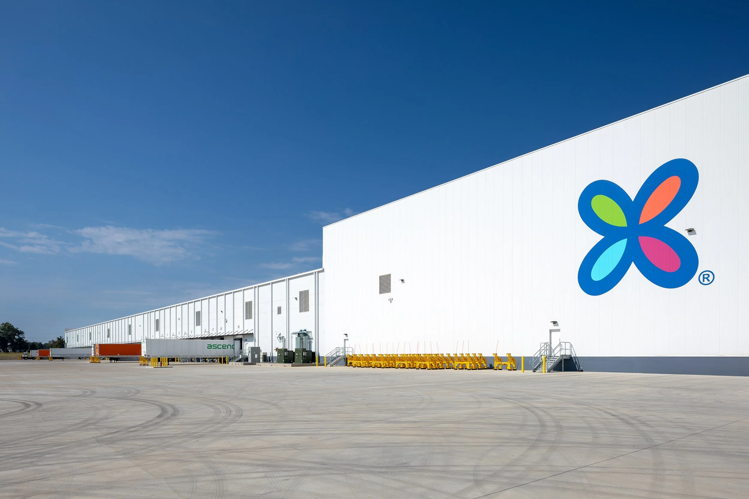 A large white industrial warehouse with a colorful Dixie product logo, yellow carts, and a clear blue sky—home to Georgia Pacific paper products.