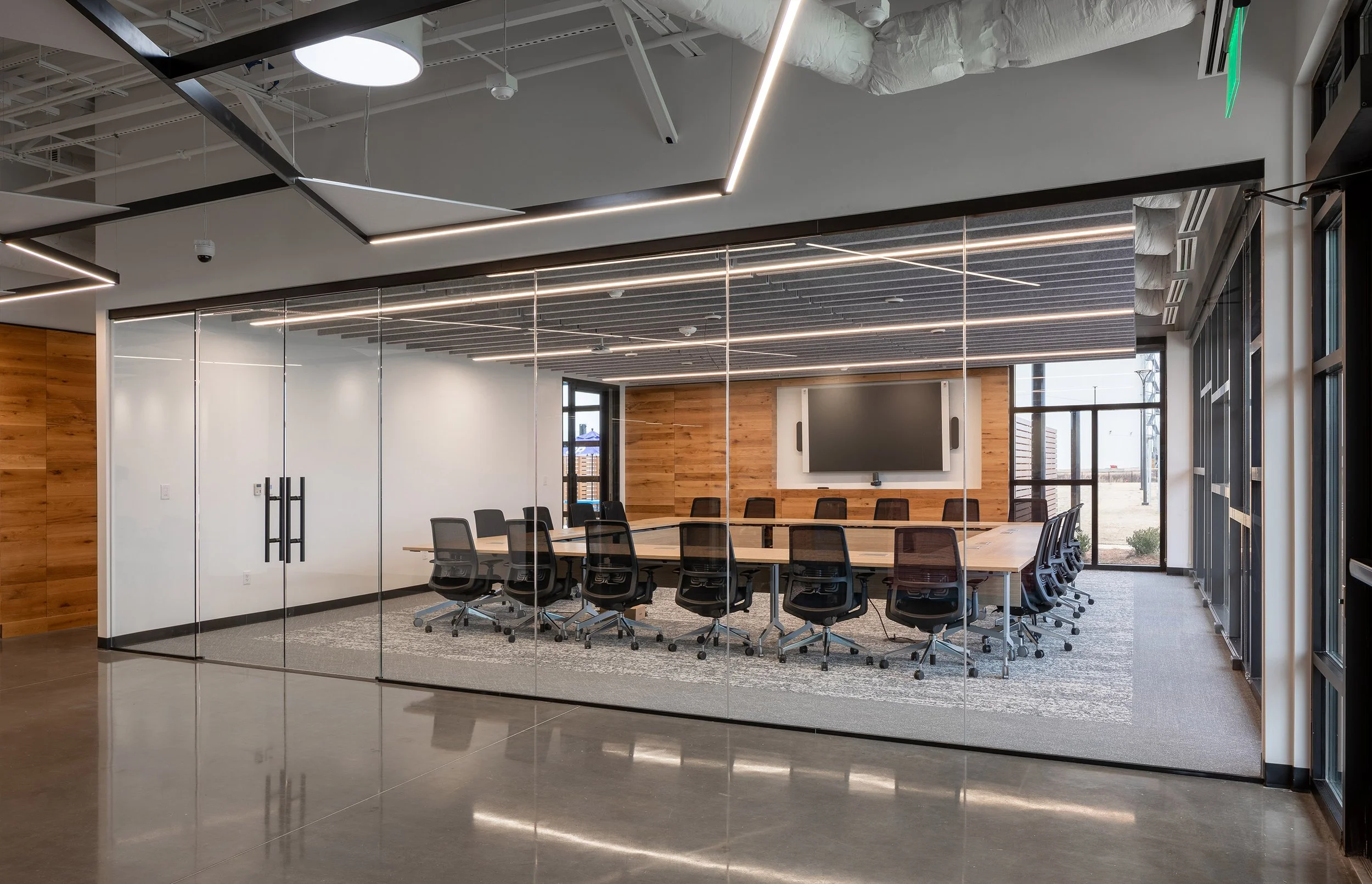 Modern conference room with a long table, office chairs, large screen, and glass walls in a sleek Macon, Georgia office setting.