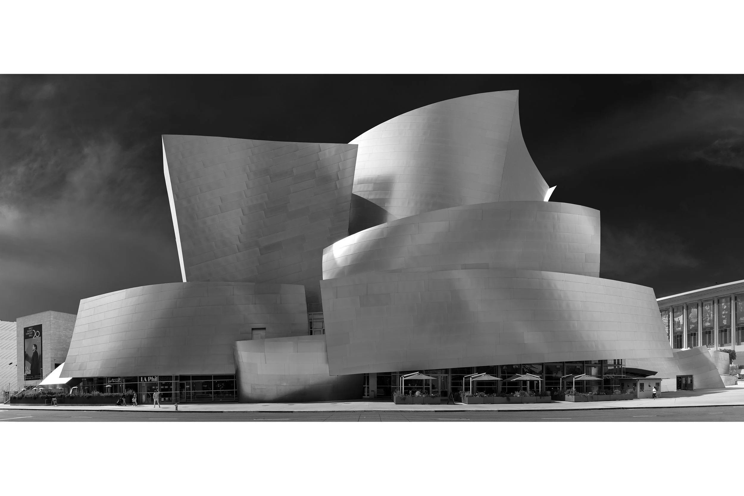 Sculptural, metallic building with curved, overlapping panels against a dark sky.
