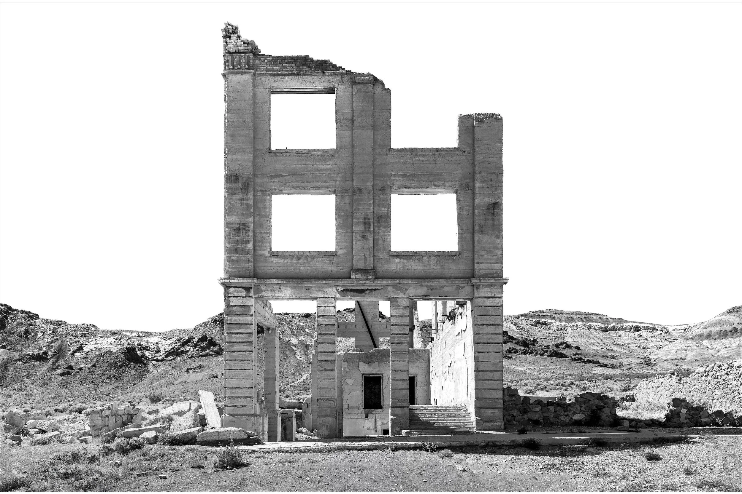 A tall, crumbling stone building rises in a barren desert landscape under a bright sky.