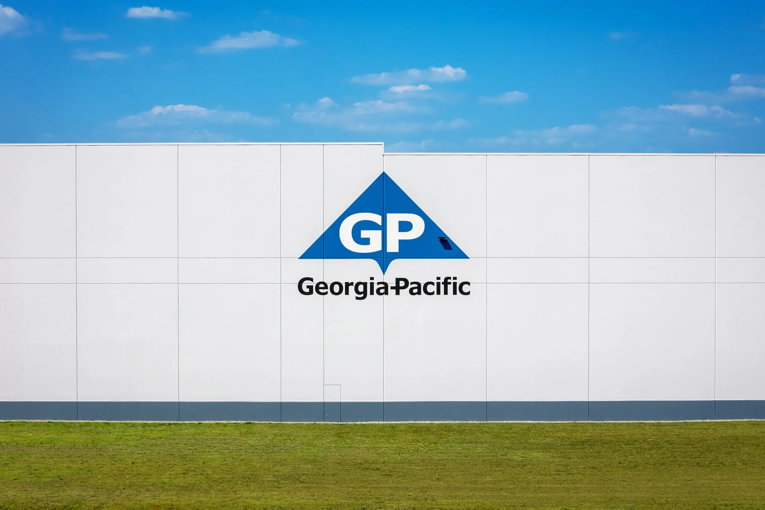The exterior of a Georgia-Pacific building, known for Dixie paper products, with the logo on a white wall under a blue sky.