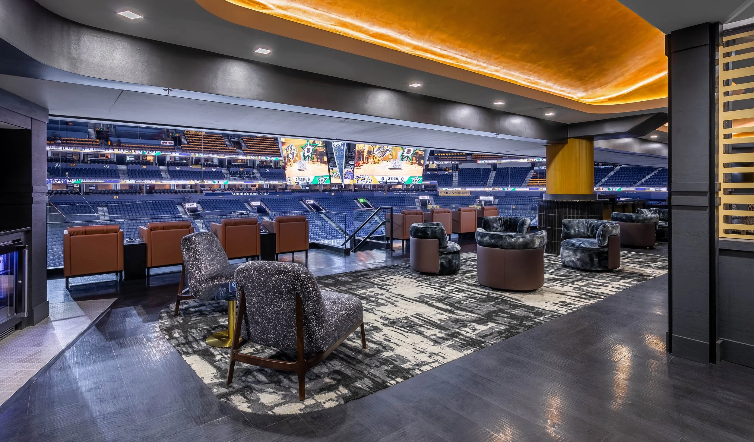 Luxury seating area overlooking Bridgestone Arena in Nashville with seats and a large scoreboard displaying game details.