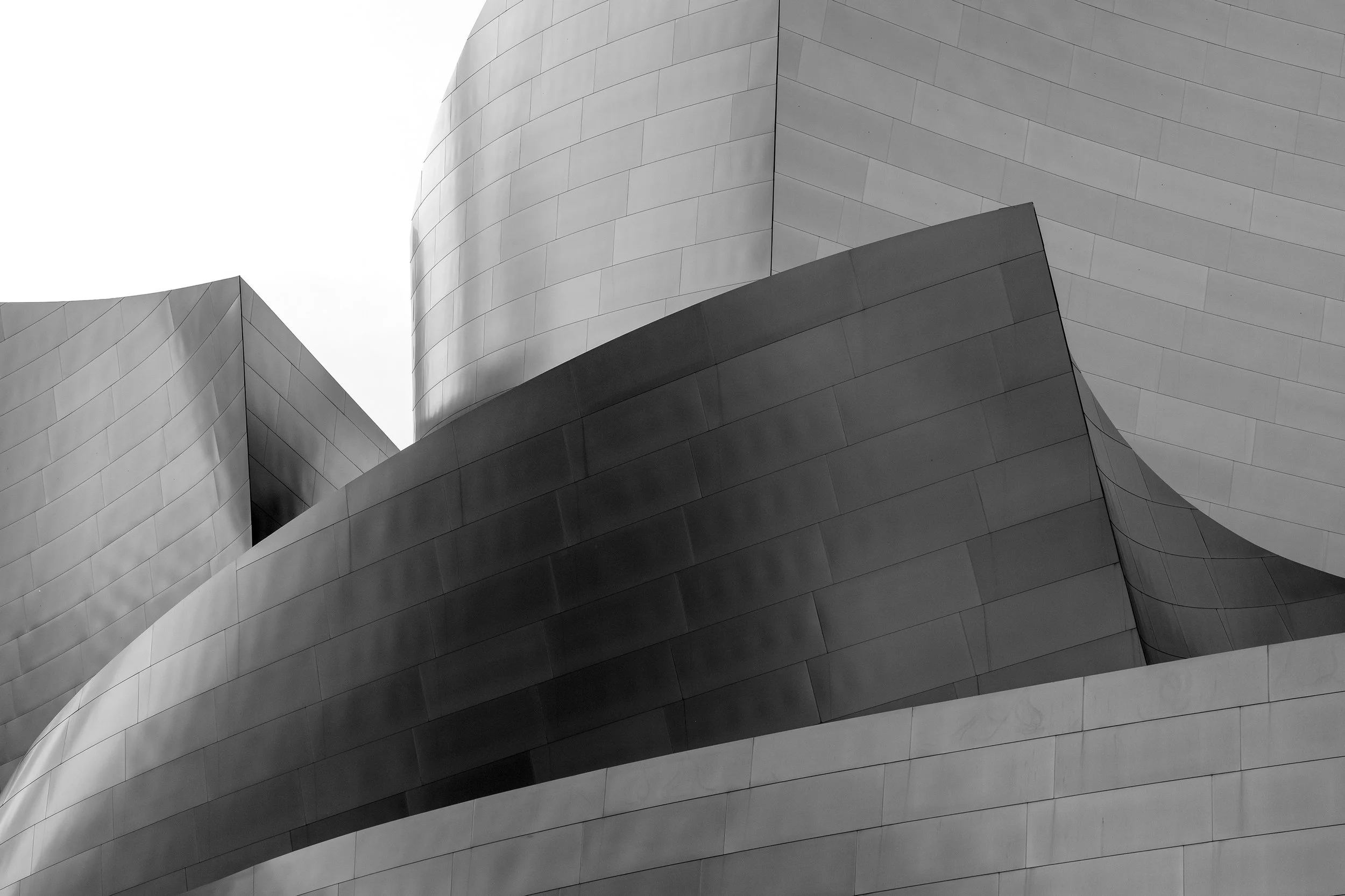 Curved, metallic architectural surfaces with smooth, reflective panels in a modern, abstract design.