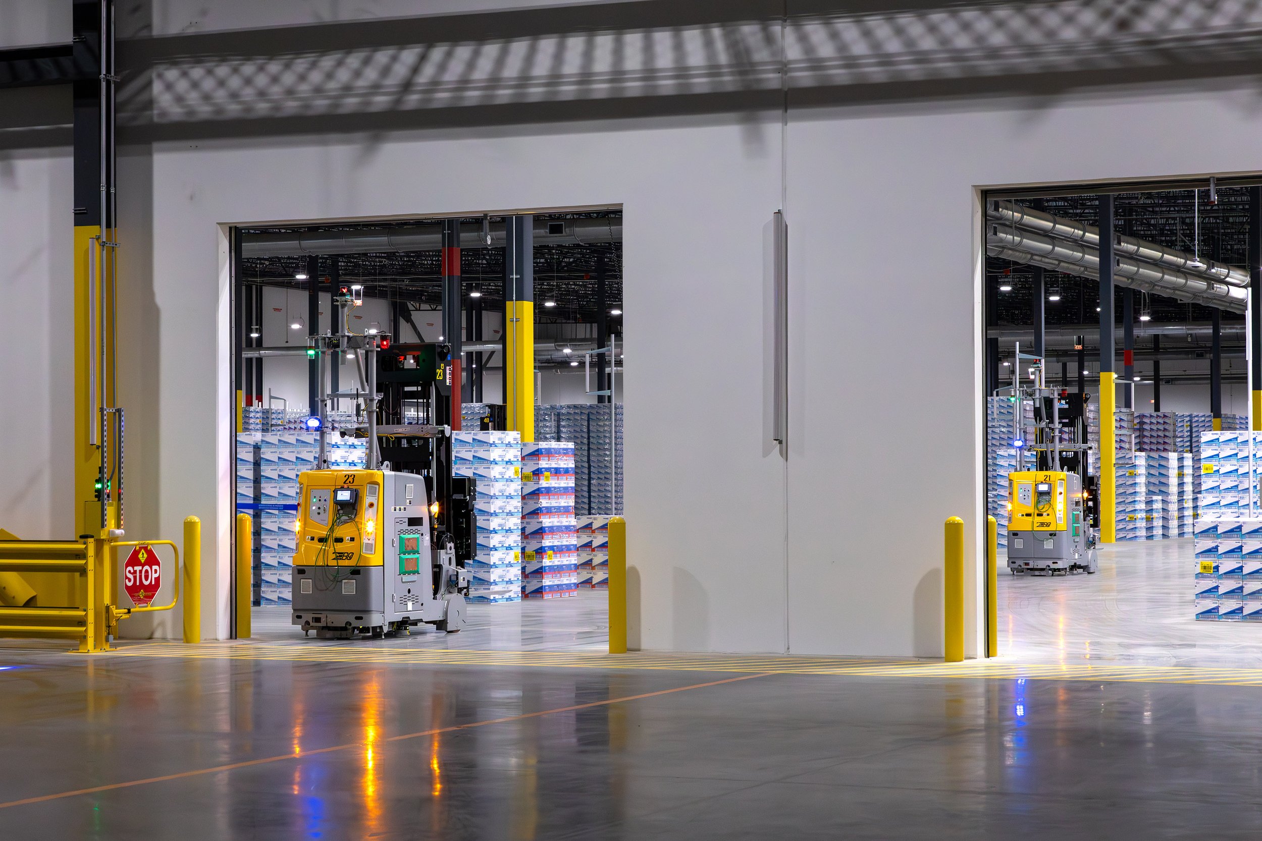 Two automated vehicles in a warehouse filled with Dixie paper products, bright lighting, and stacked pallets for distribution.