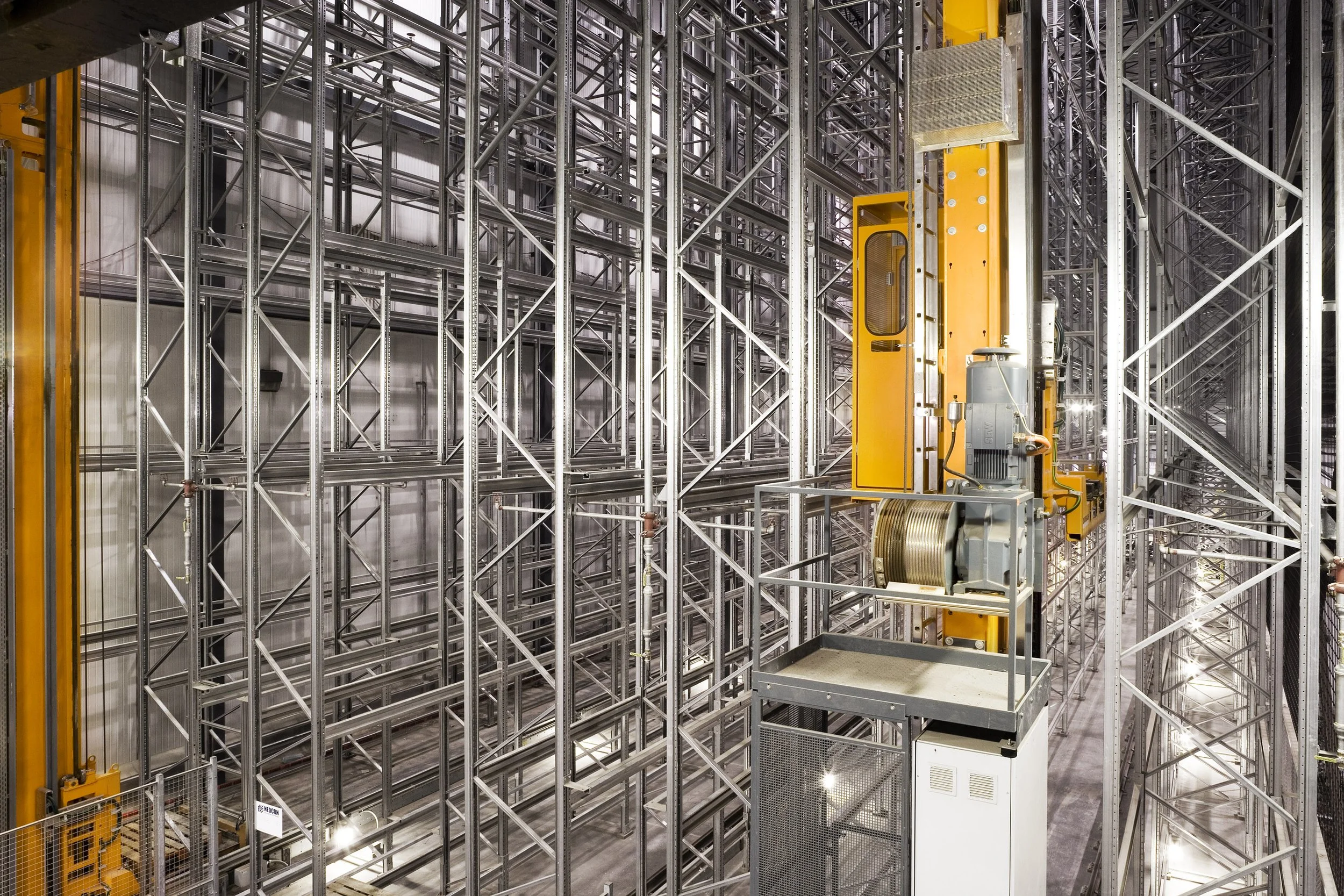 Automated warehouse project with tall metal racks, robotic crane, and bright industrial lighting for food storage.
