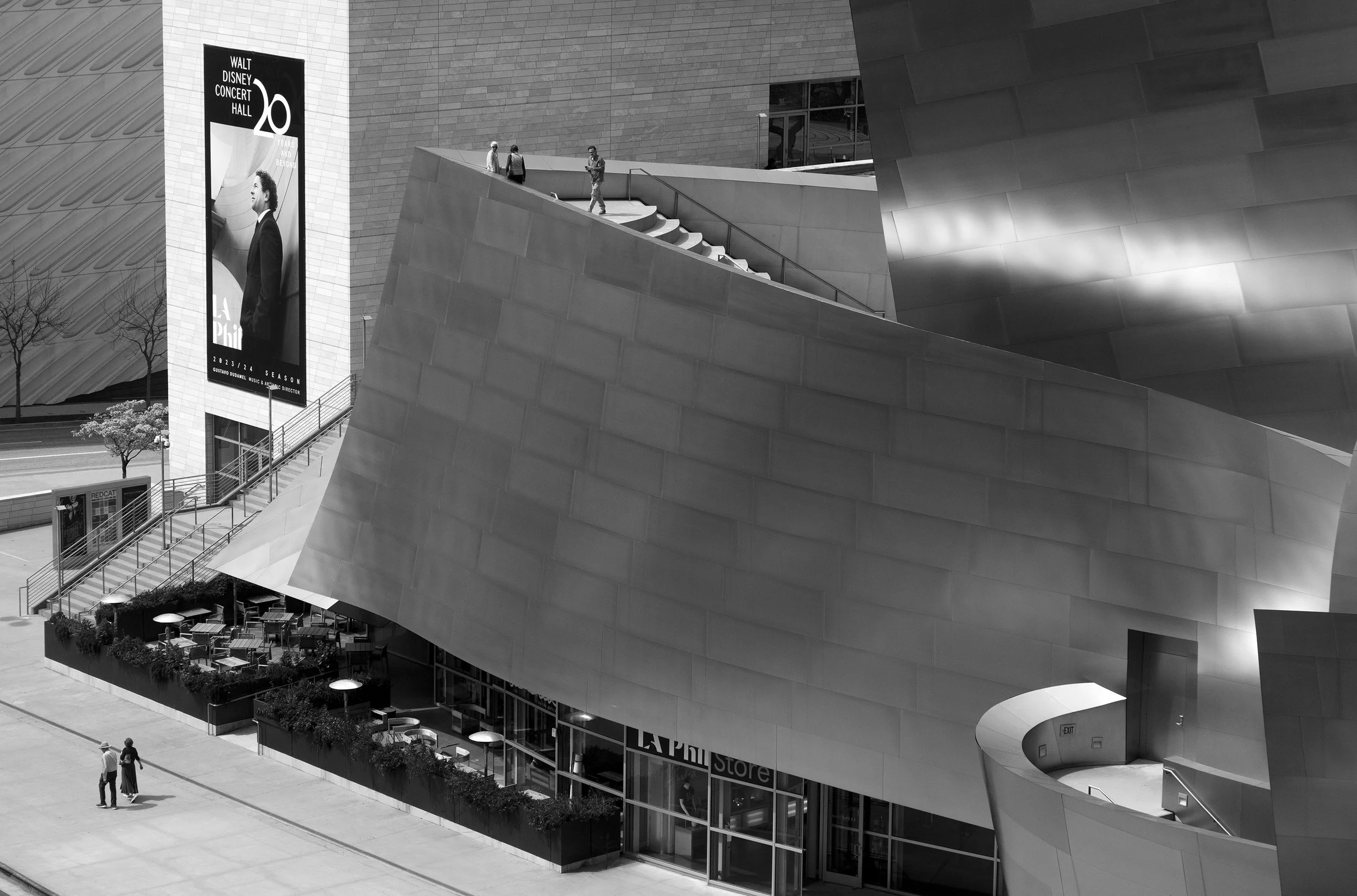 Black and white photo of Walt Disney Concert Hall exterior with people on stairs and outdoor seating below.
