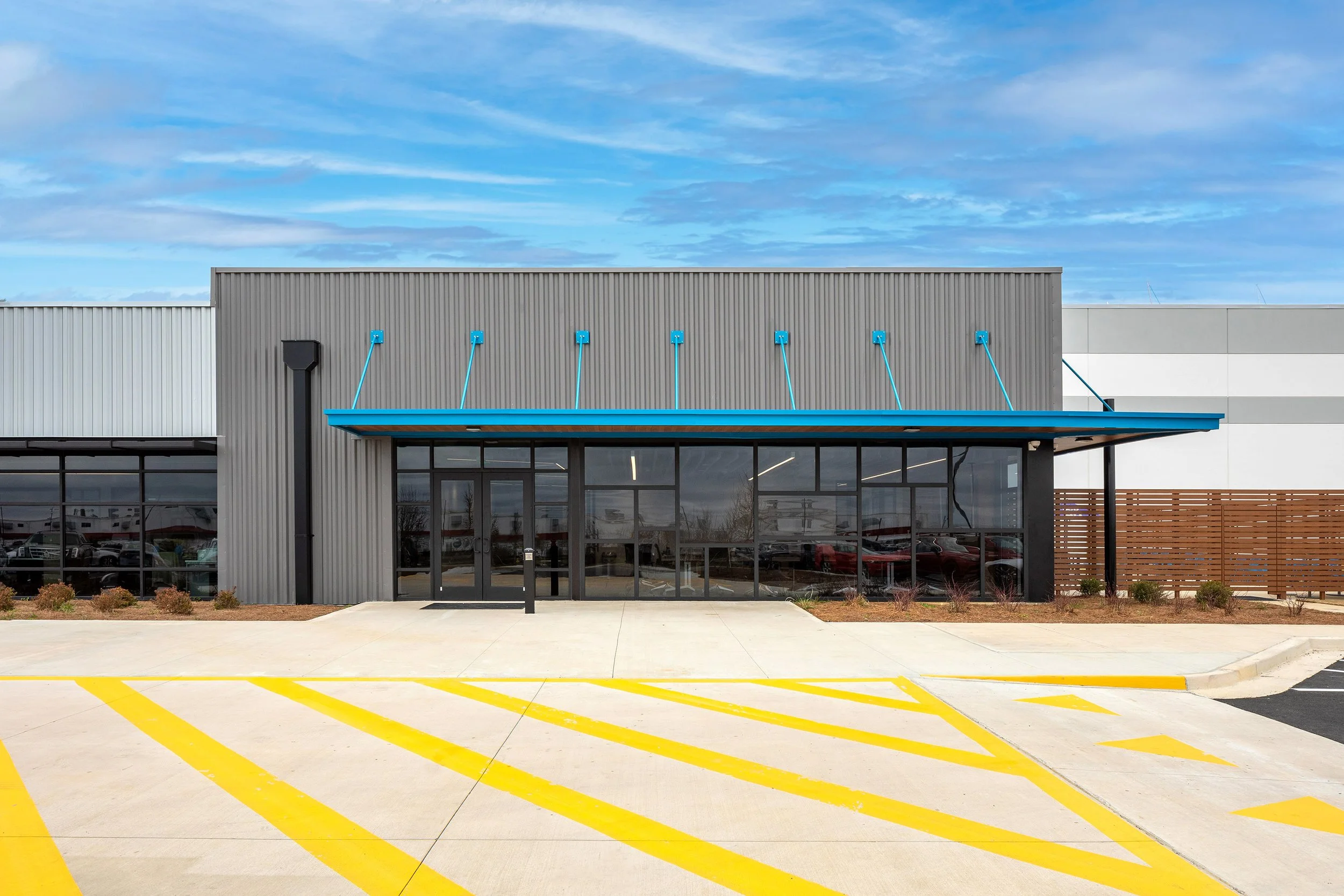 Modern industrial building in Macon with large glass doors, blue awning, and yellow-striped pavement—ideal for automation businesses.