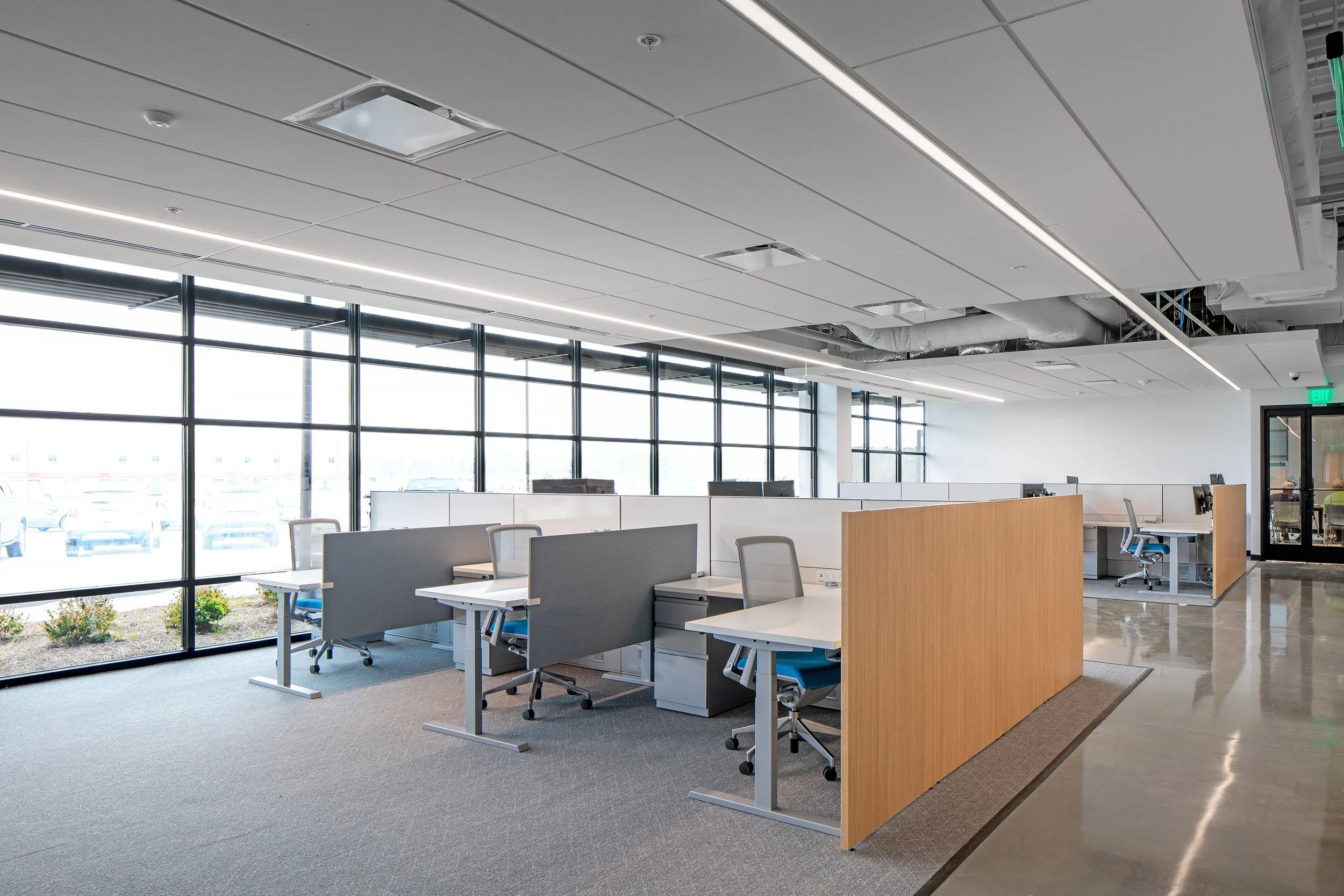 Modern open-plan office in Macon with several workstations, industrial accents, glass windows, and bright natural lighting.