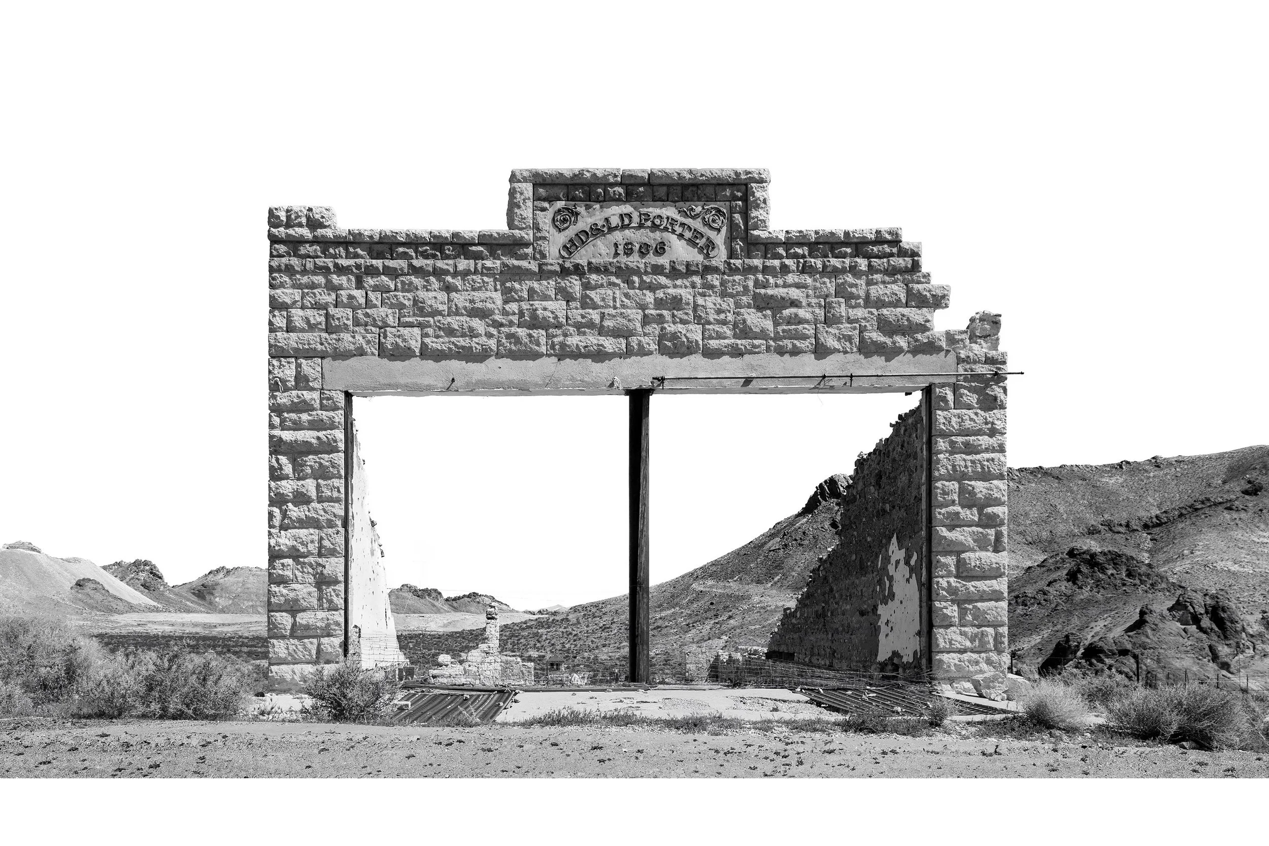 Black-and-white photo of a stone building ruin labeled Porter 1906 in the desert landscape of Death Valley.