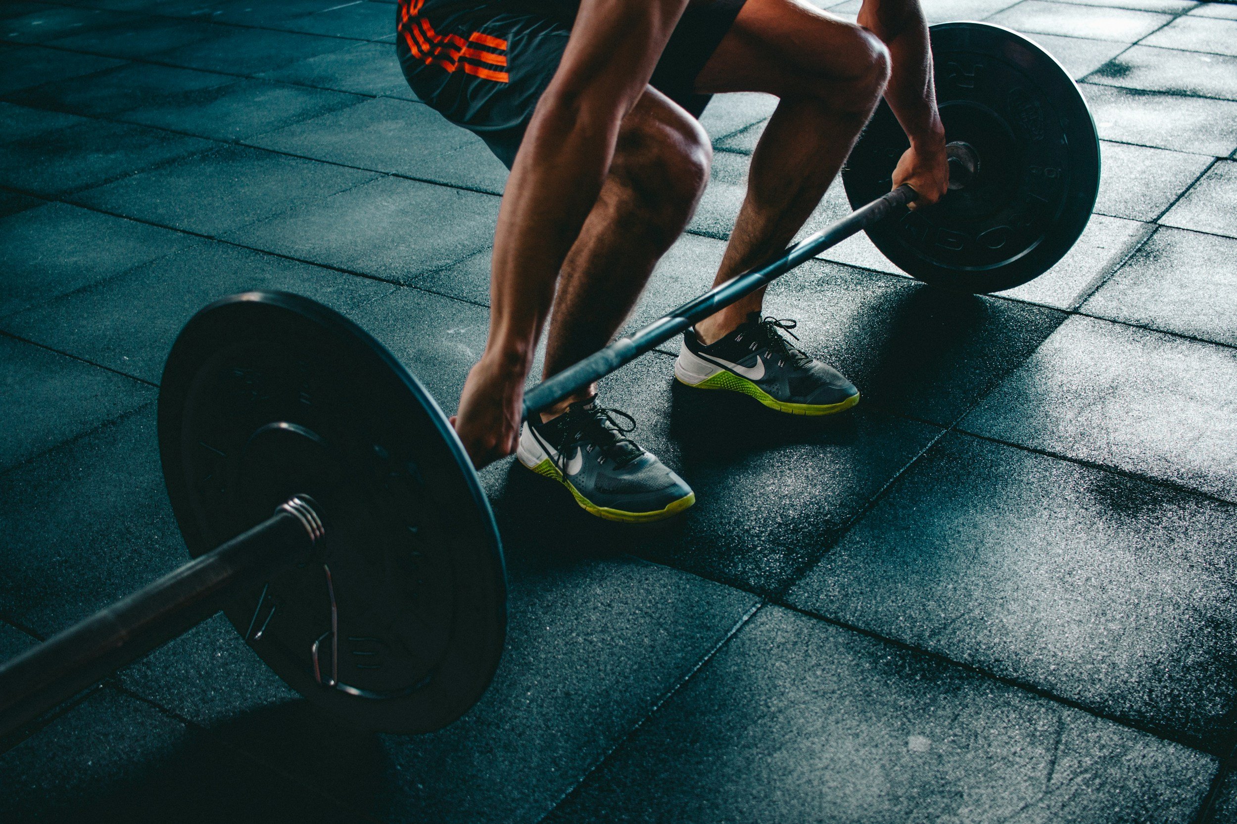 A person is in a gym lifting a barbell with weights during a workout.