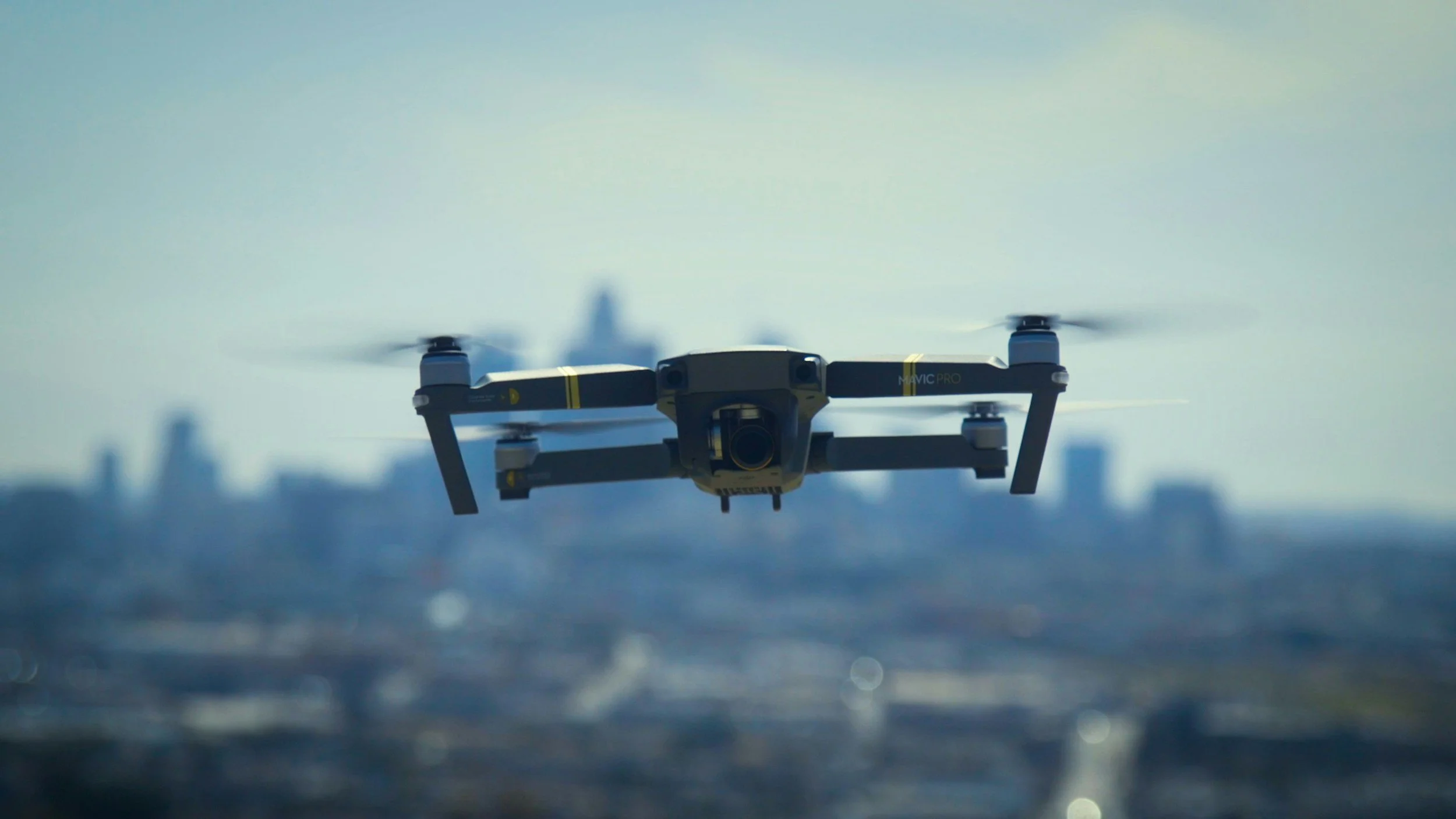 A drone flying over a city skyline with buildings in the background