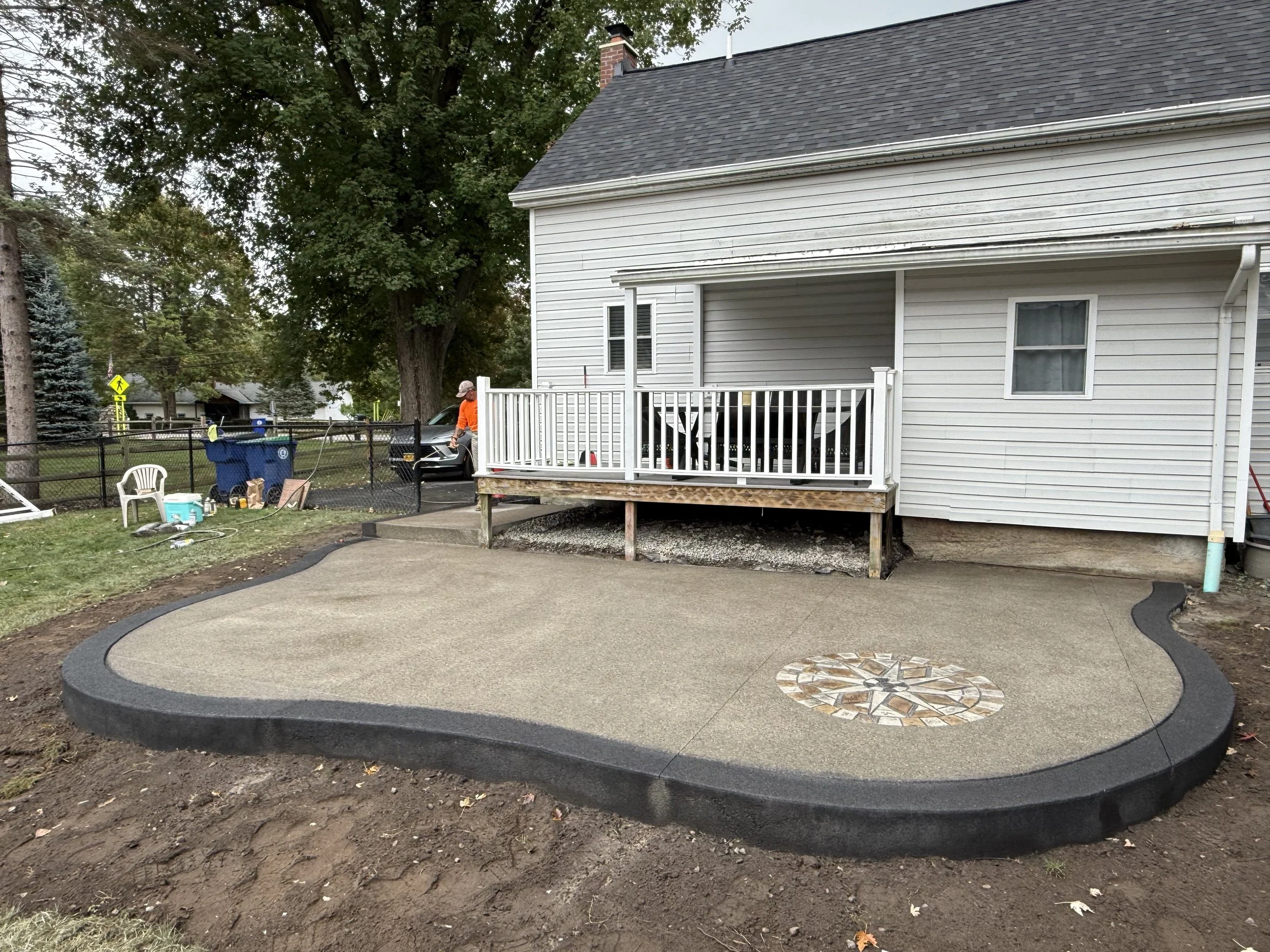 Backyard patio with a new porched area, a circular mosaic design, and a landscaped border, with a question mark in the center.