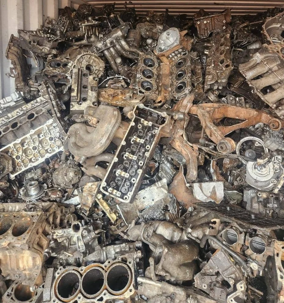 Pile of used and rusty car engine parts and metal scraps.