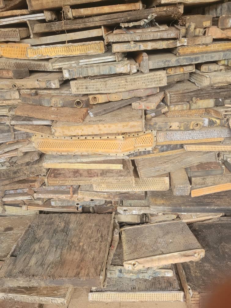 A large pile of various old wooden and metal molds or stamps stacked together. Some molds are yellow, others are gray or brown, with different textures and patterns.