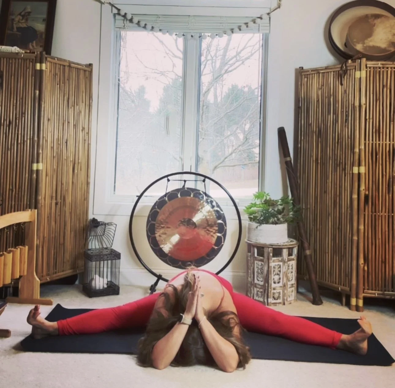 Person practicing yoga in a split pose with hands in prayer position in a meditation room.