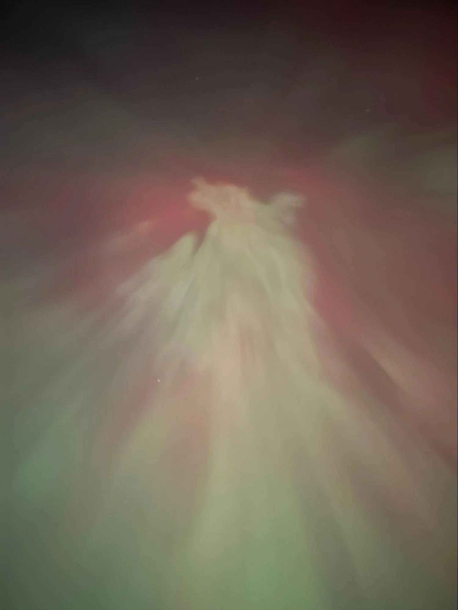 Night sky with a few stars and a cloud at the horizon, with a reddish glow on the cloud.