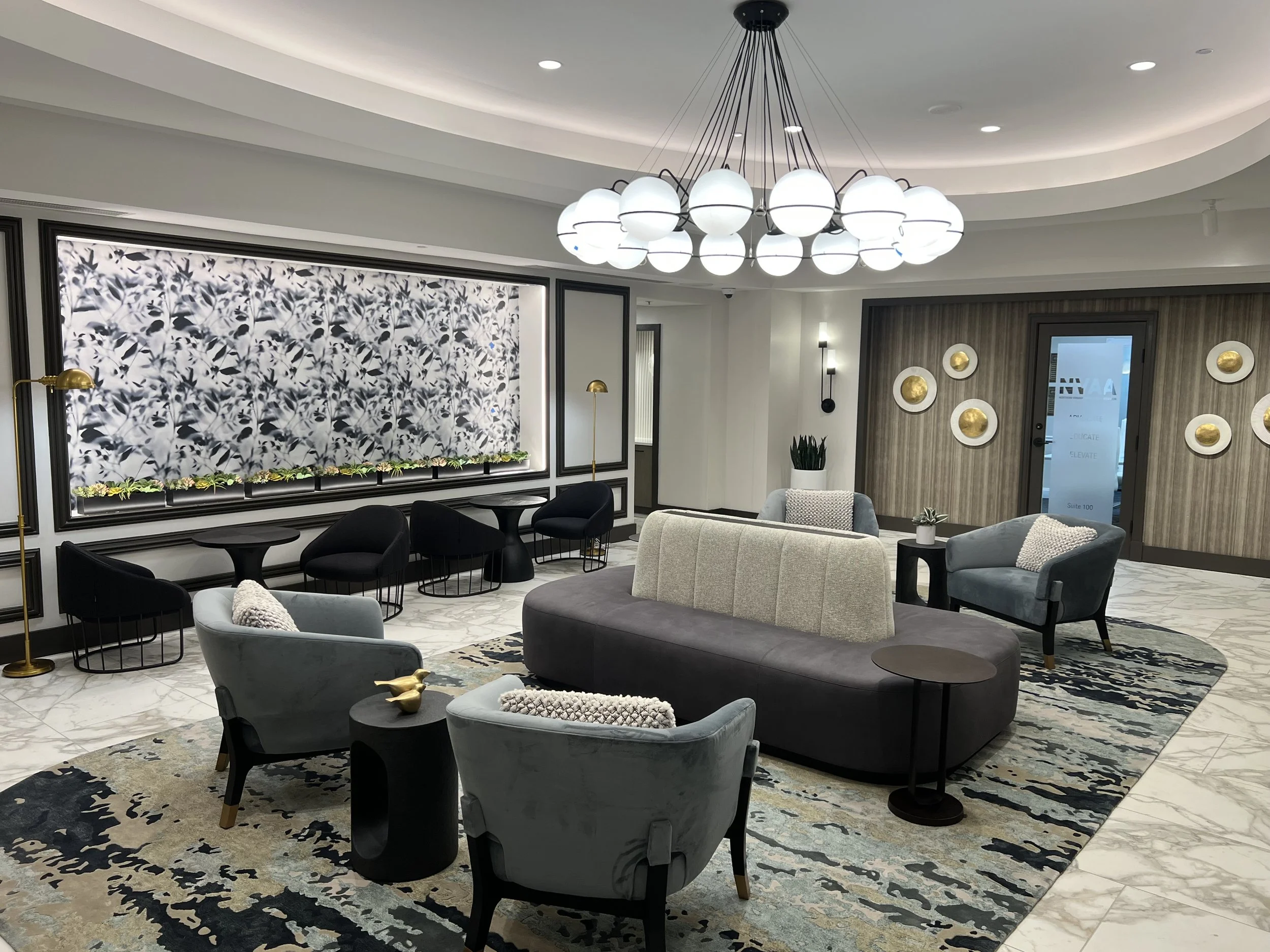 Empty elegant hotel lobby with a modern chandelier, marble floors, and decorative wall panels.