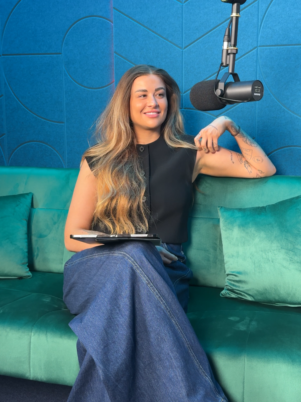 Founder of ELOWO, Emma sitting on a green sofa smiling off camera