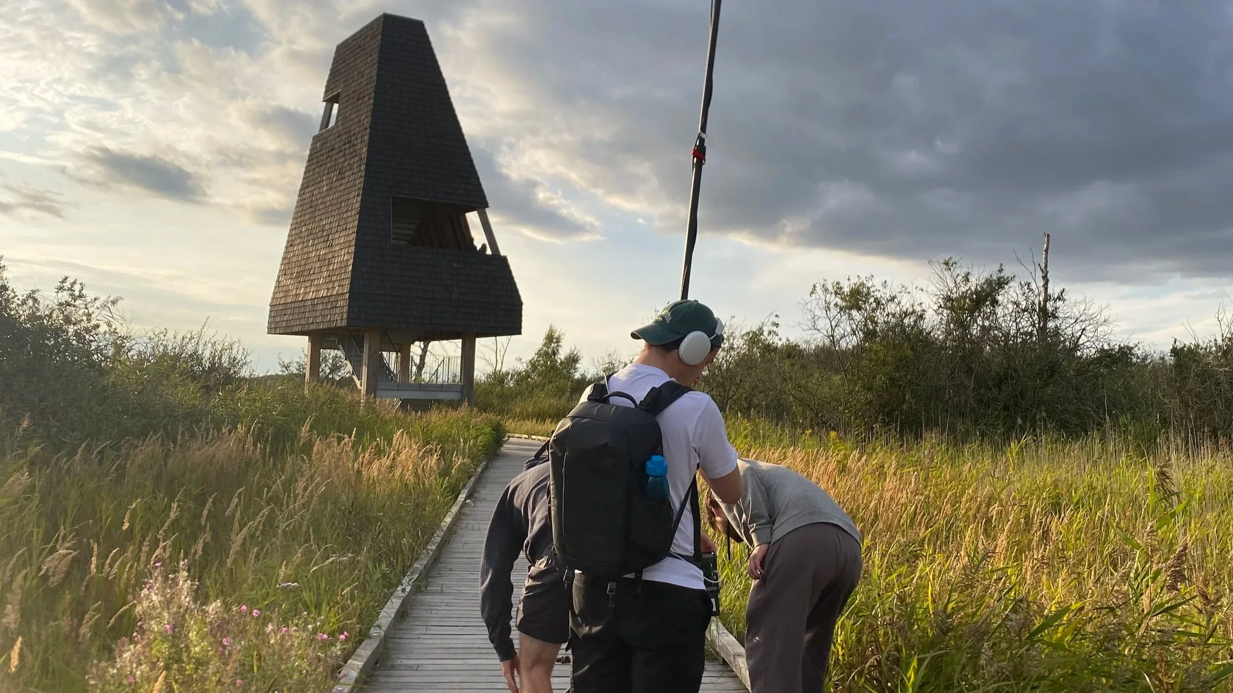 People filming a scene of a man serving food at a table during a production in a bright sunlit dining room.