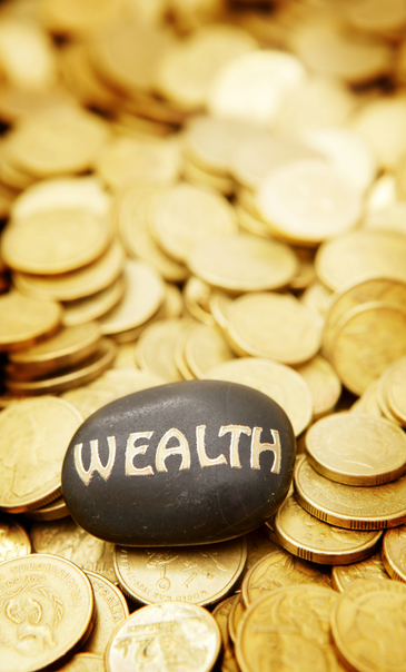 A black stone with the word 'WEALTH' written on it, surrounded by numerous gold coins.