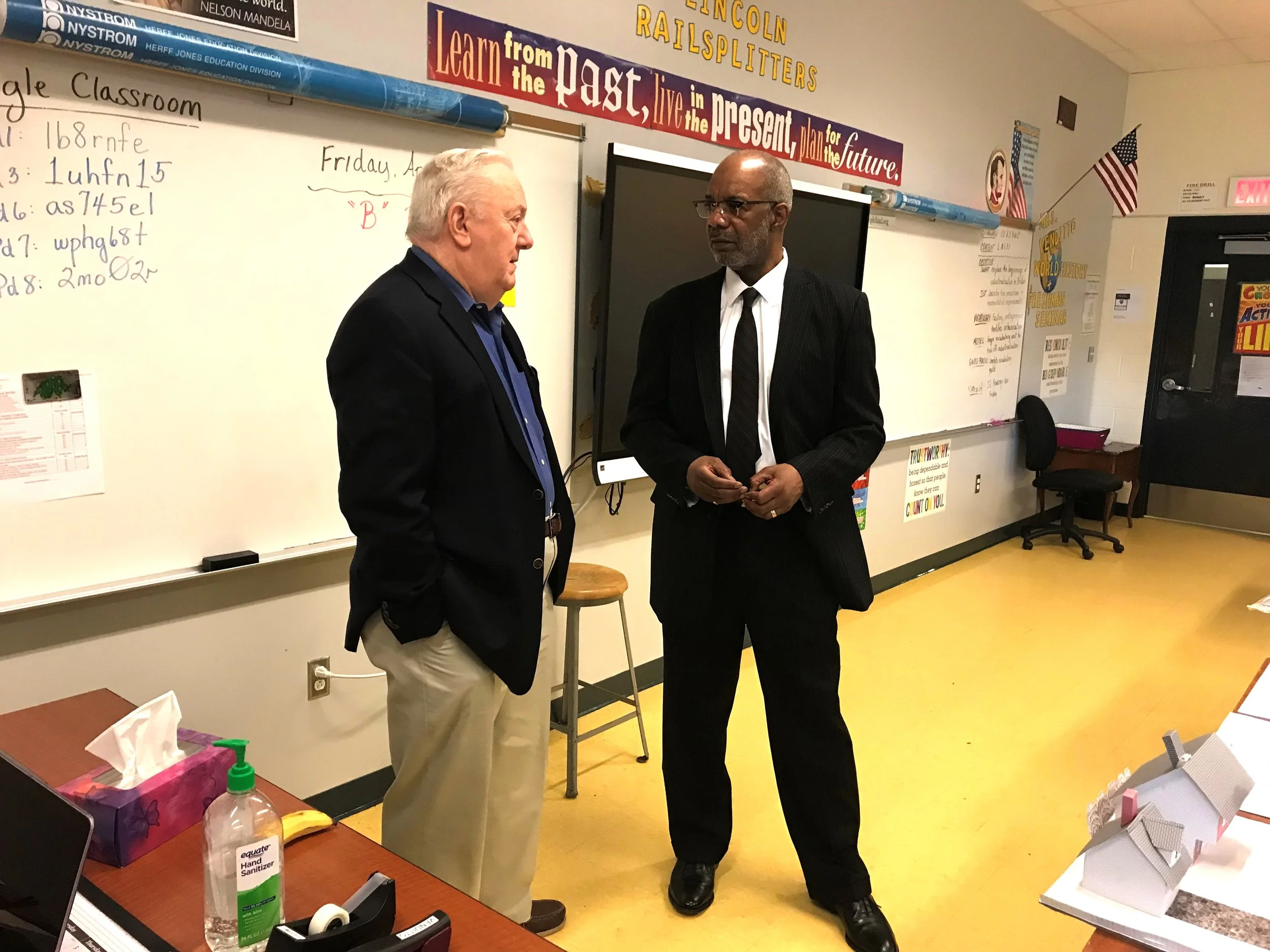 Two project-management educators talking beside a classroom whiteboard