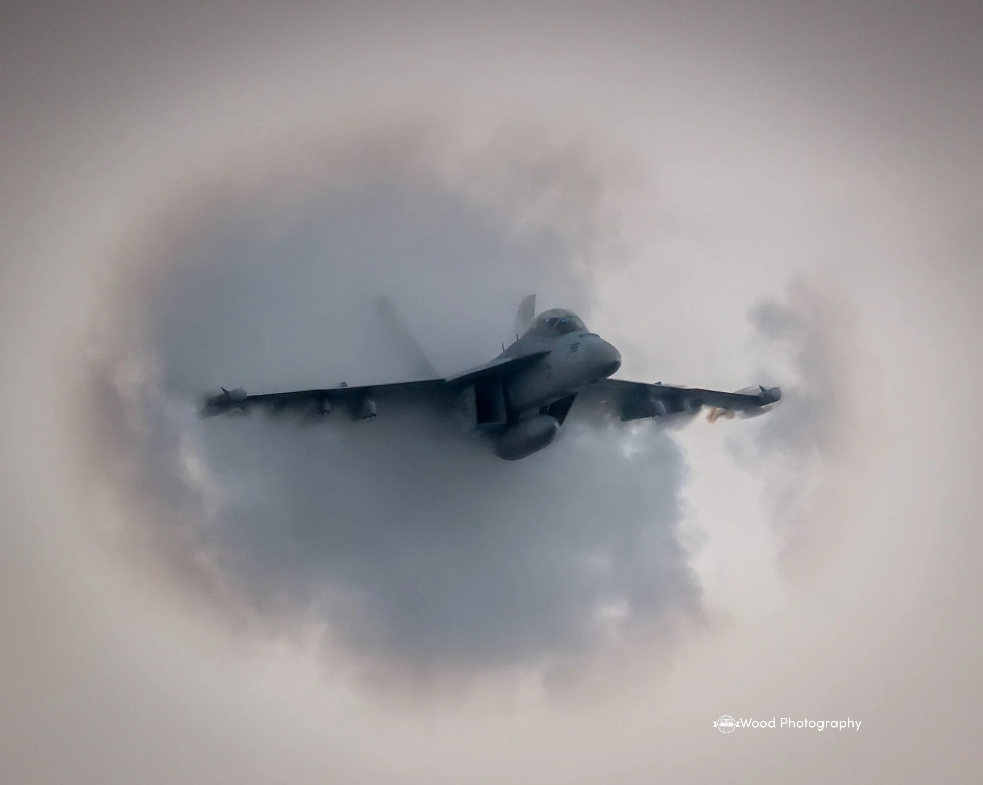 A jet airplane flying through cloudy sky.