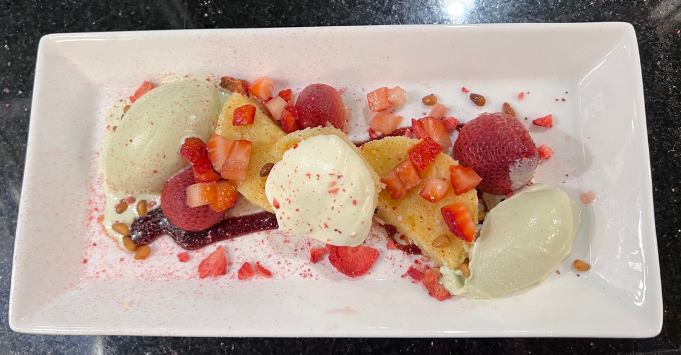 Dessert plate with strawberries, small pineapple slices, sorbet, and sauce/mix of diced fruit.