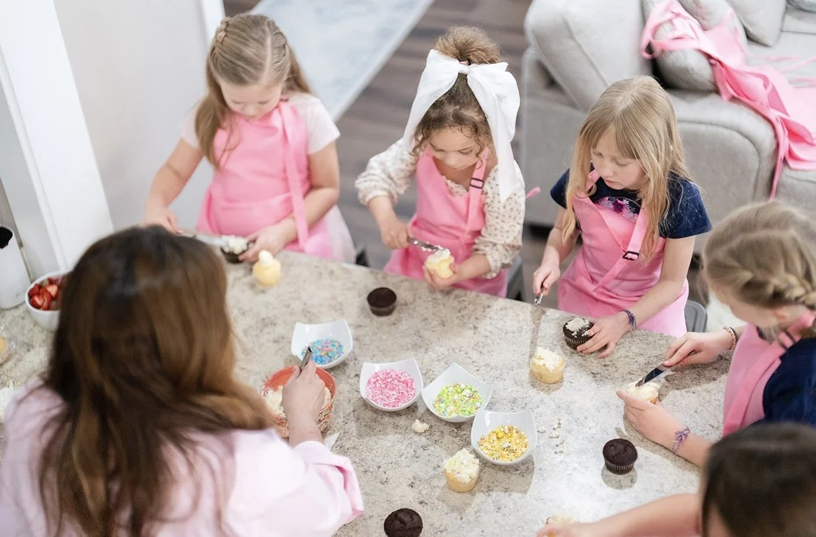 Children decorating cupcakes with sprinkles and frosting at a birthday party.