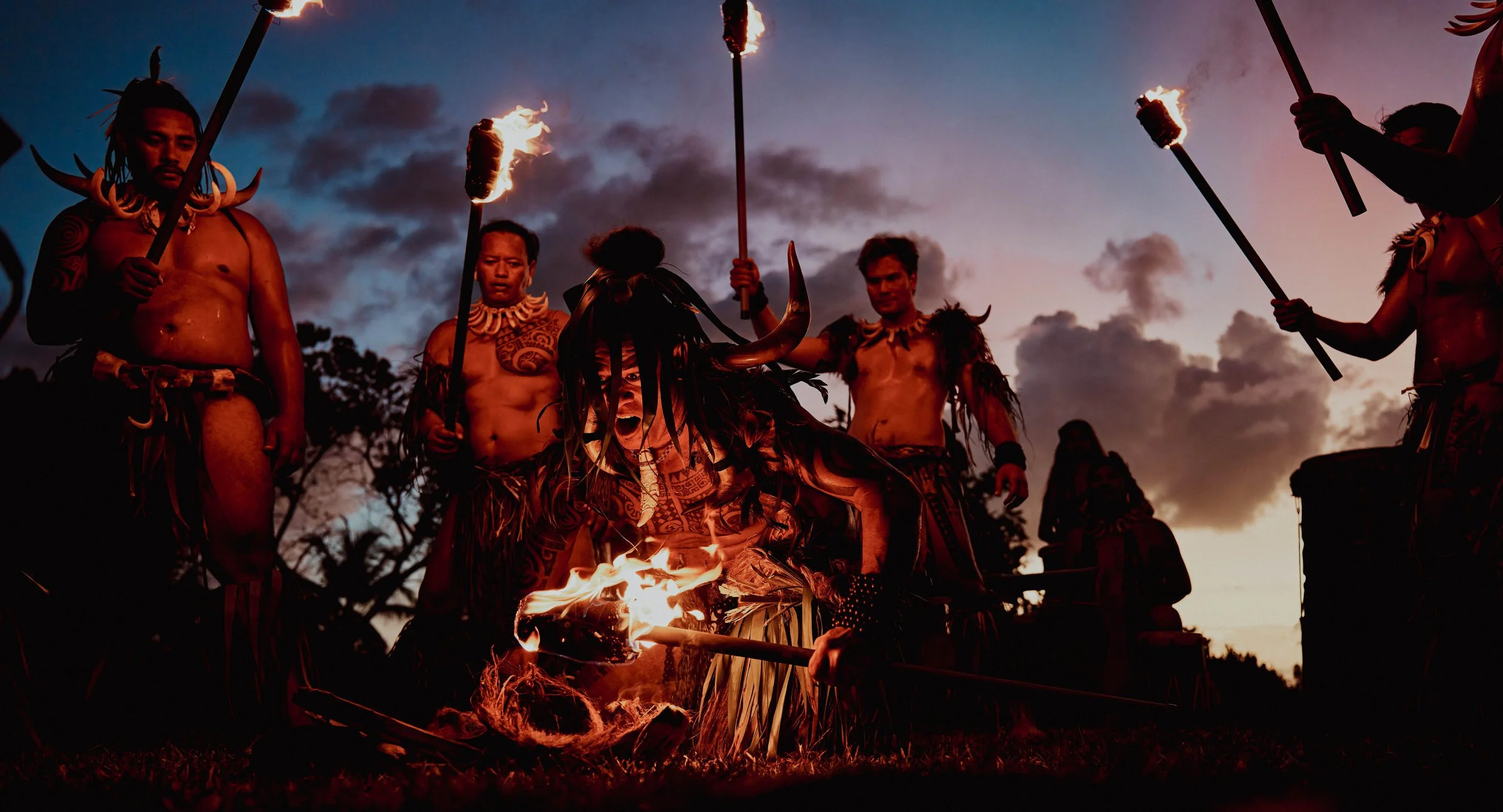 Marquisiens lors d'une cérémonie avec torches en plein air au crépuscule.