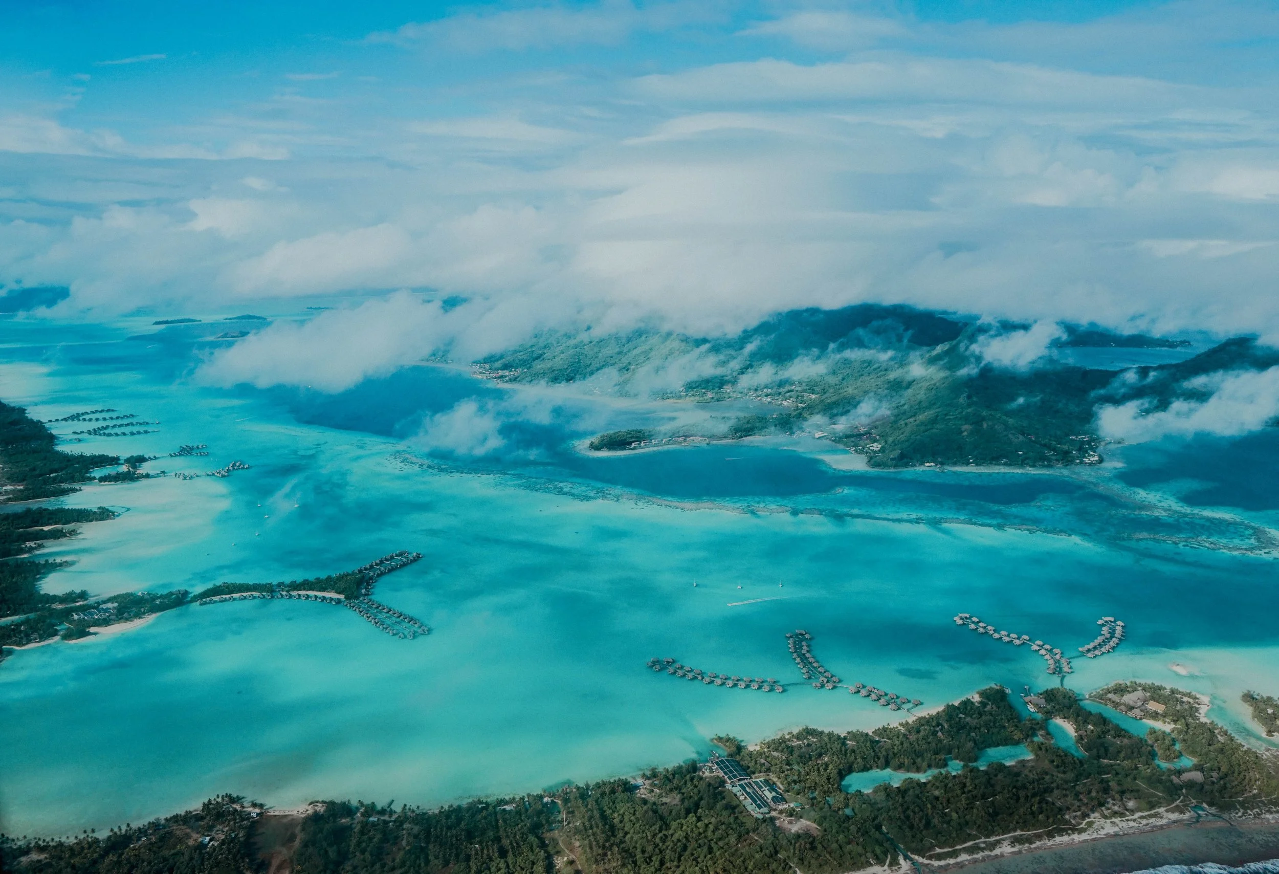 Vue aérienne d'un paysage tropical avec des eaux turquoise, des îles, des montagnes verdoyantes et des nuages dans le ciel