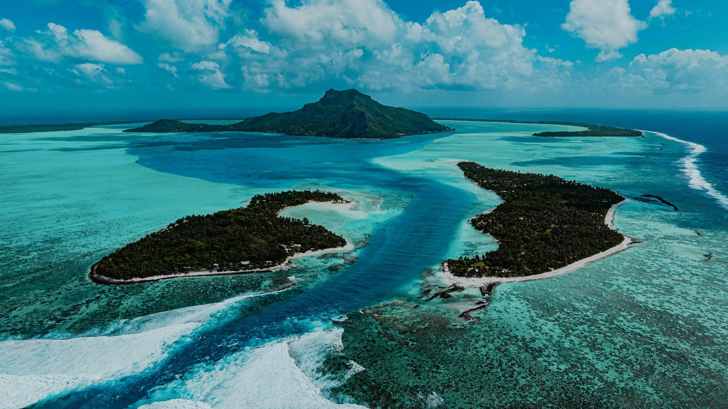 Vue aérienne de l'île de Moorea en Polynésie française, entourée d'eaux turquoise, avec une montagne centrale et plusieurs lagons et plages entourant l'île.