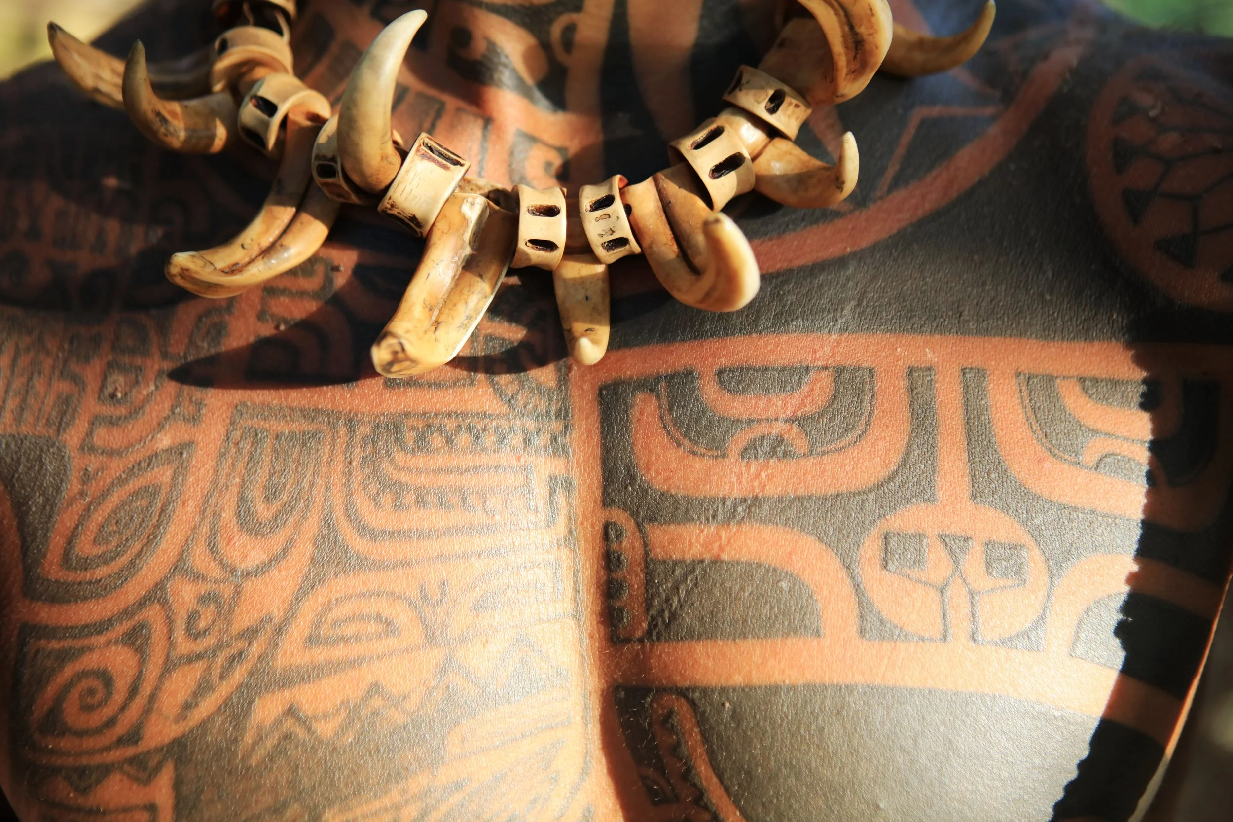 Un collier de dents ou de coquillages posé sur un tissu tacheté avec un motif marquisien.