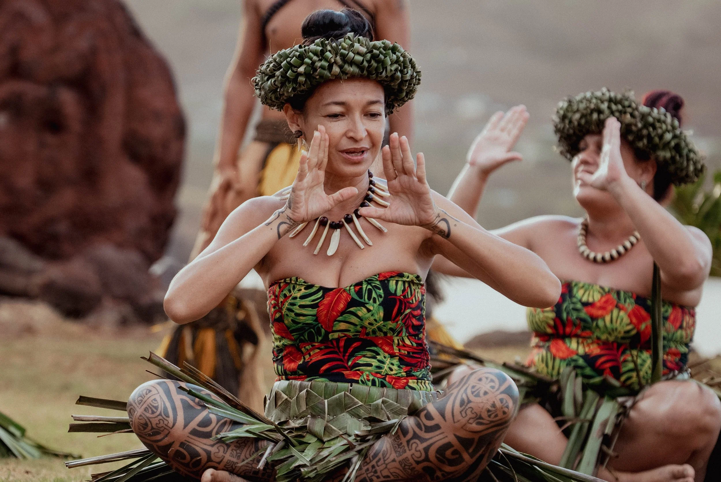 Marquisiens en train de danser, portant des vêtements traditionnels et des faux bijoux, dans un paysage extérieur.